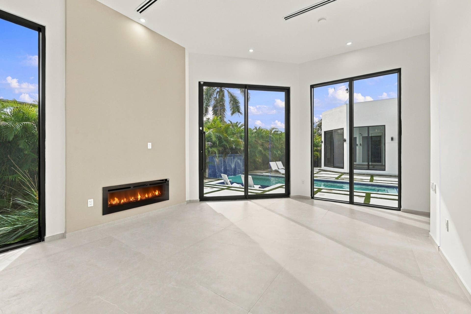 Bright, open-concept living space featuring polished concrete flooring, recessed ceiling lighting, and a linear electric fireplace with black surround