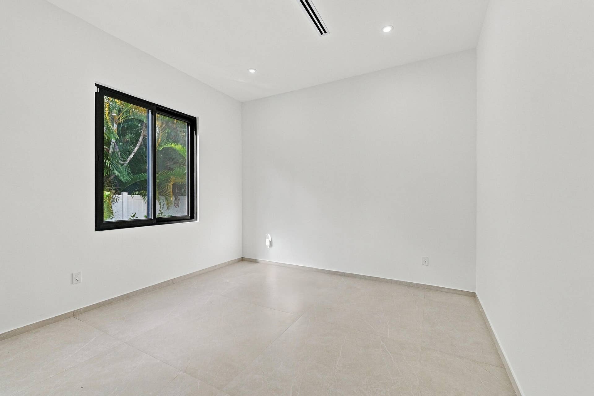 Bright, minimalist bedroom showcasing polished concrete flooring, clean white walls, and abundant natural light from a black-framed window