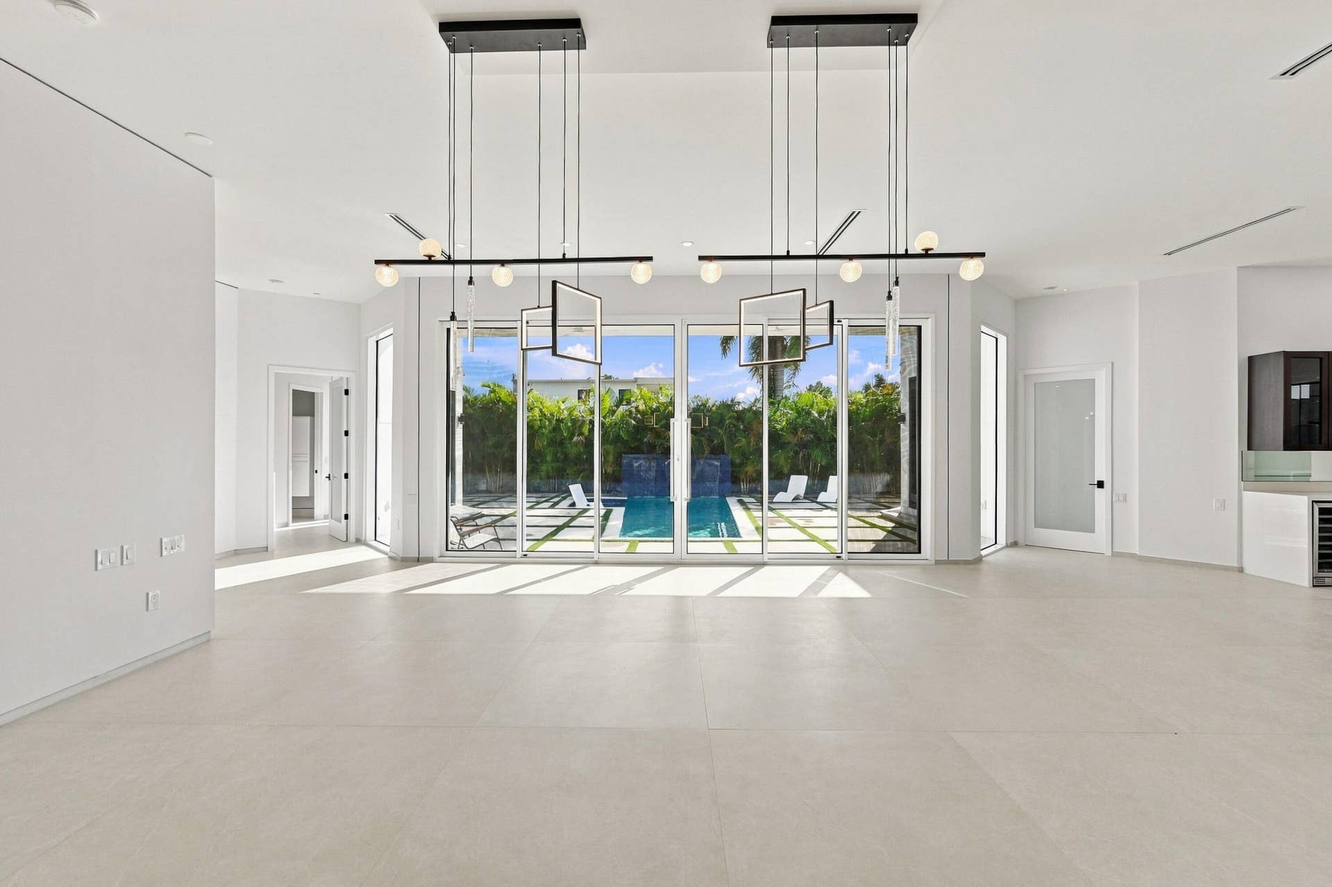 Expansive open-concept room with light-toned flooring and multiple floor-to-ceiling glass sliding doors