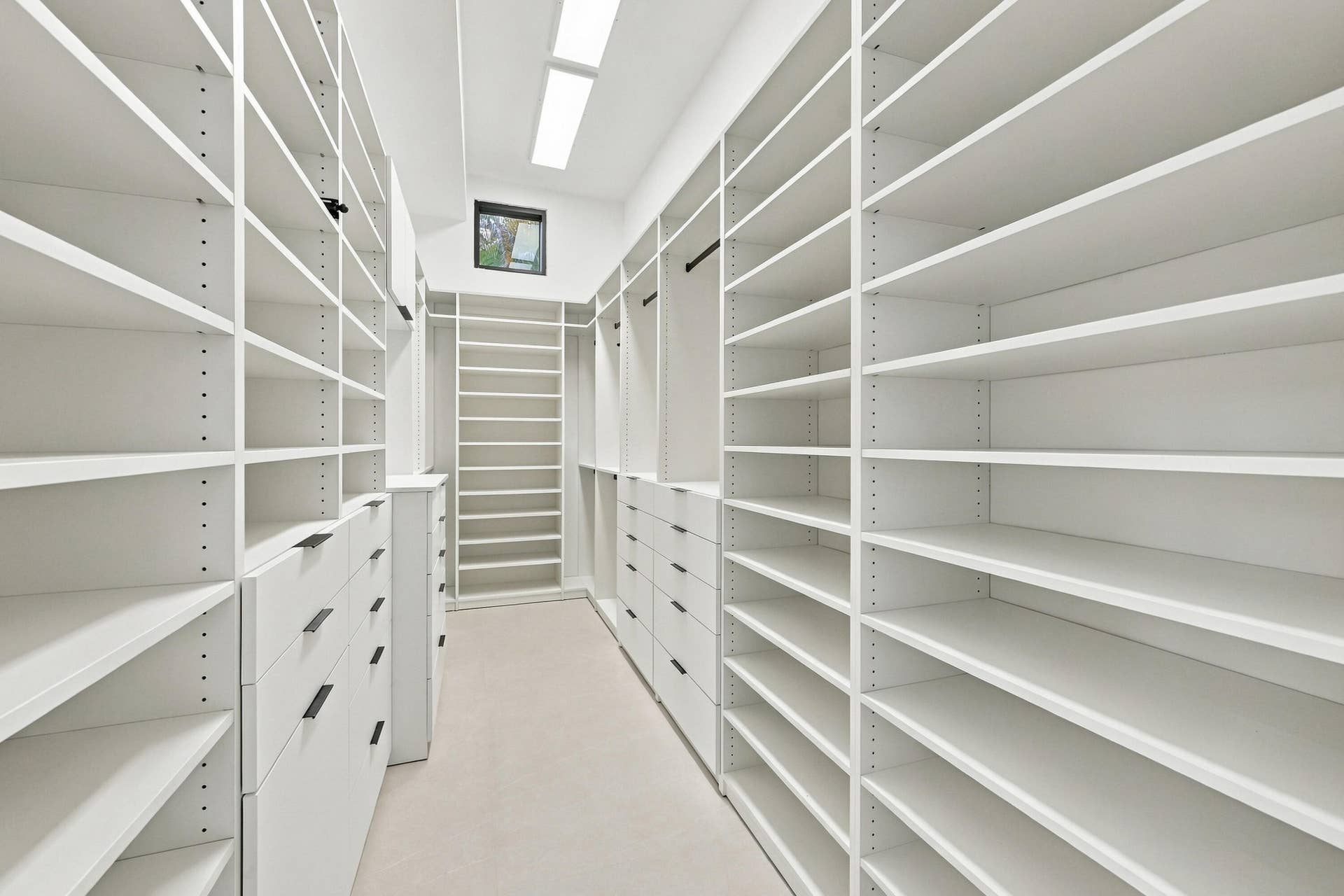 Custom closet system featuring extensive shelving, built-in drawers with modern pulls, and integrated lighting