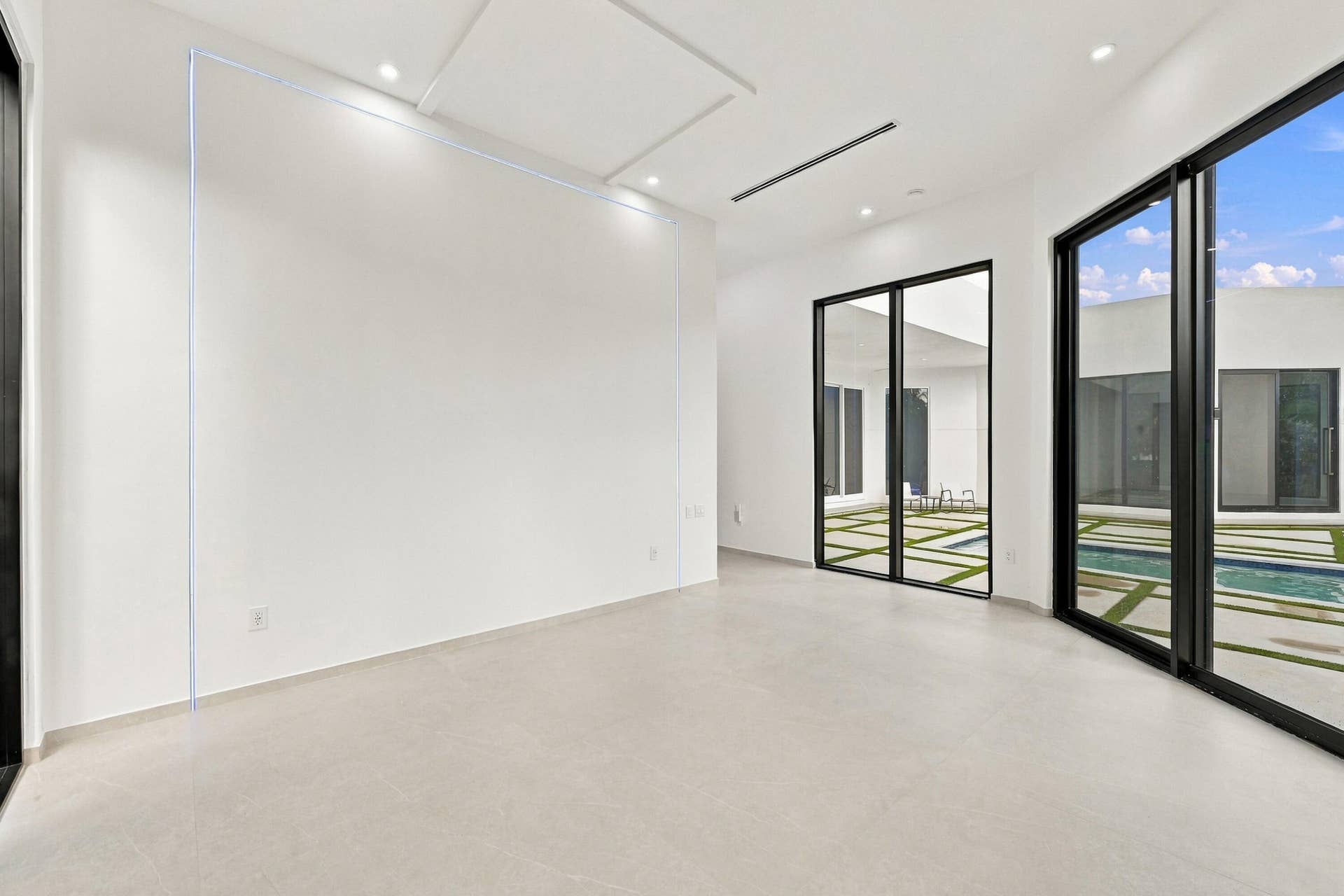 Bright, open interior space featuring polished concrete flooring, floor-to-ceiling glass doors with black aluminum framing, and recessed ceiling lighting