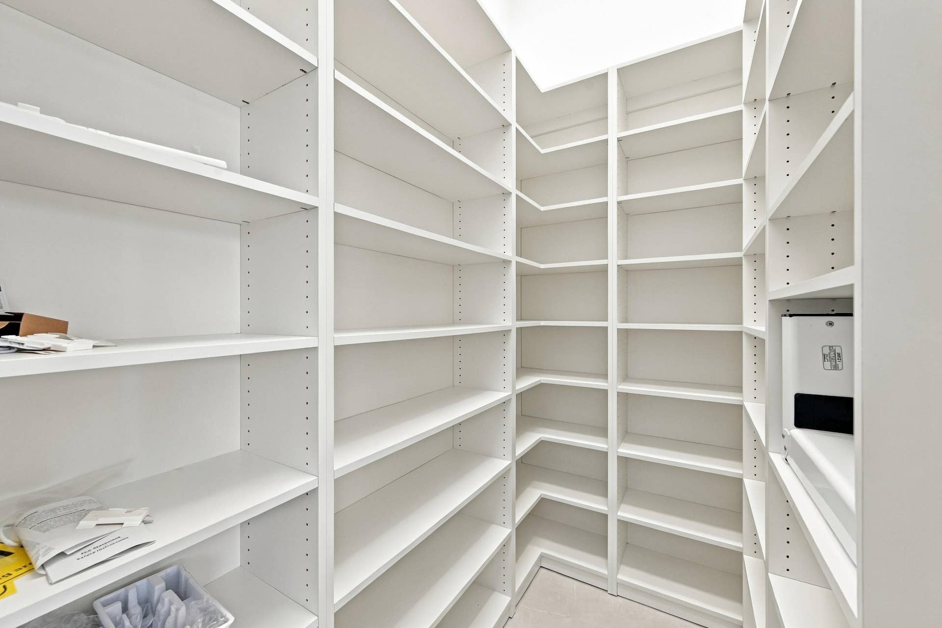 Spacious pantry featuring extensive built-in shelving with adjustable shelves throughout, white finish cabinetry, and bright overhead lighting