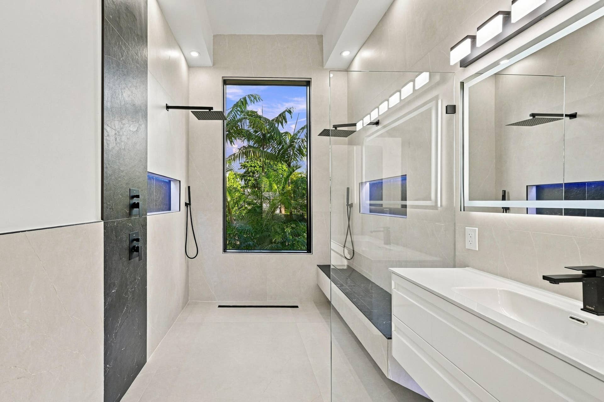 Spa-inspired primary bathroom featuring dual vanities with white cabinetry, quartz countertops, and matte black fixtures