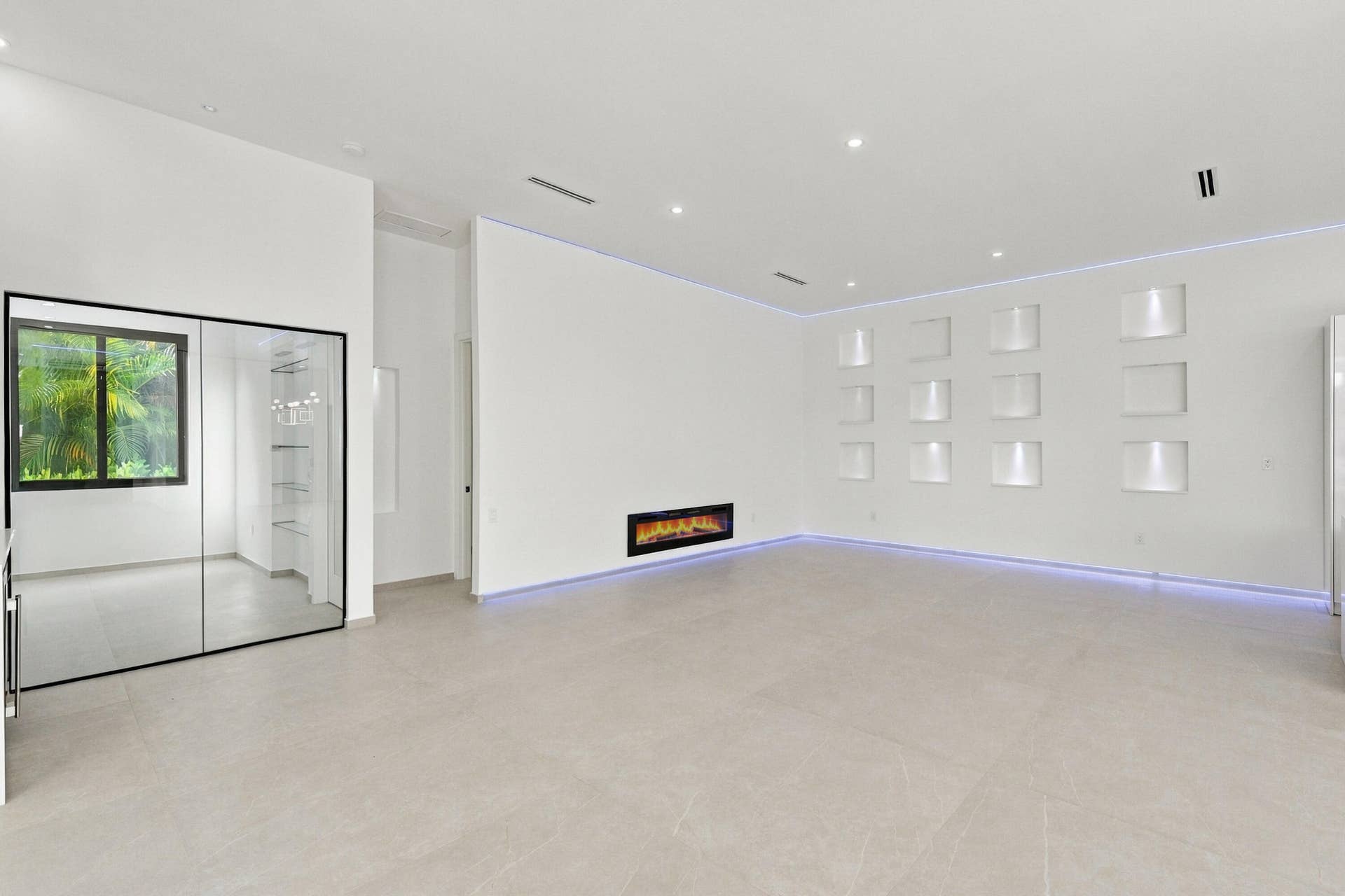 Spacious open-concept room featuring polished concrete flooring, recessed ceiling lighting, and a linear electric fireplace