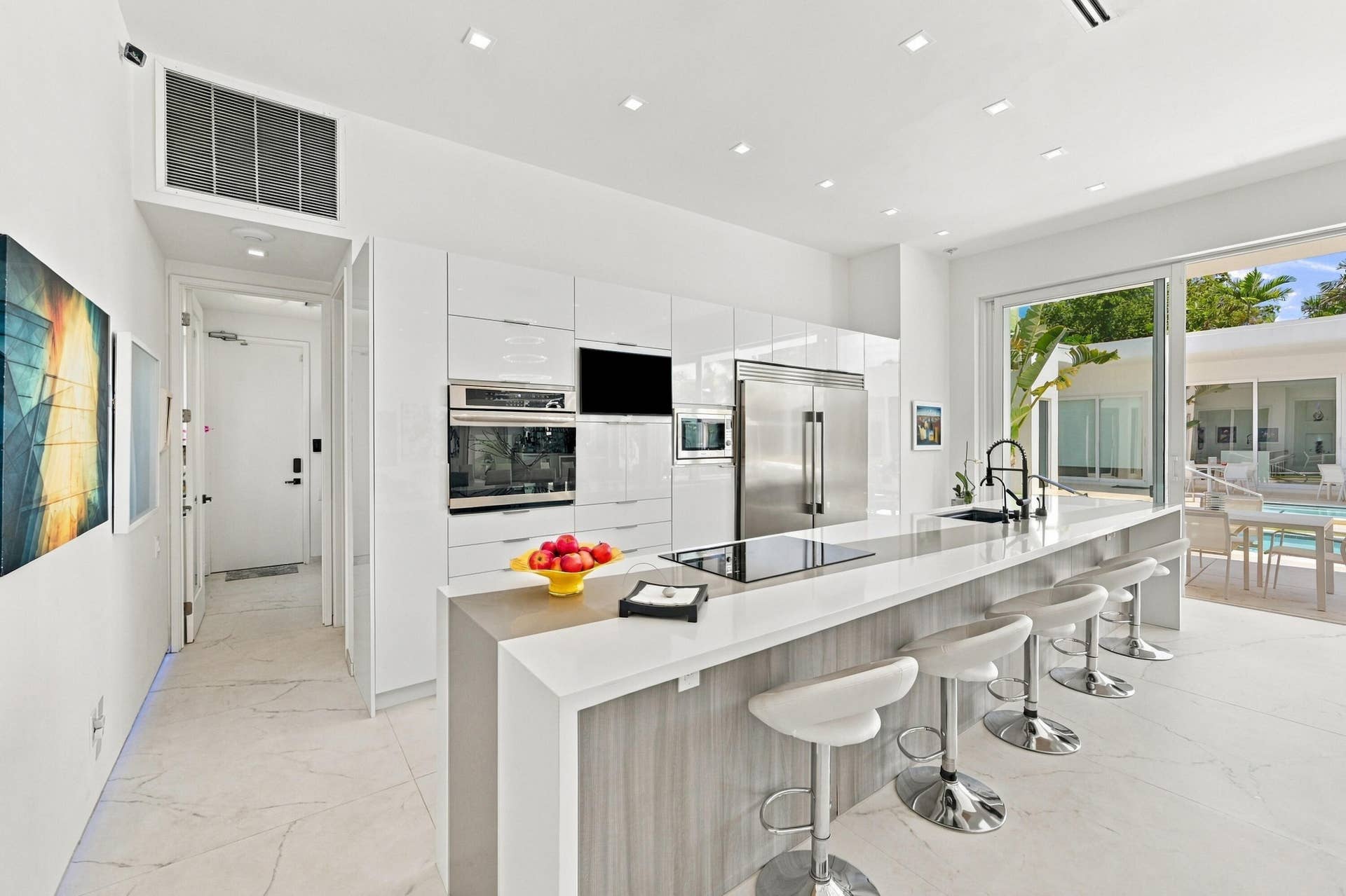 110 NE 16TH Place, Fort Lauderdale, FL 33305 Modern kitchen featuring white cabinetry, integrated stainless steel appliances, a center island with cooktop, and large sliding glass doors