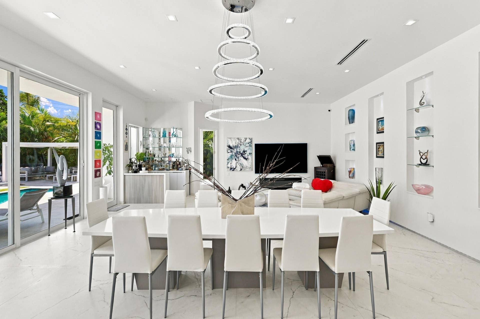110 NE 16TH Place, Fort Lauderdale, FL 33305 White tile flooring, custom built-in shelving, recessed ceiling lighting, and a contemporary ring chandelier