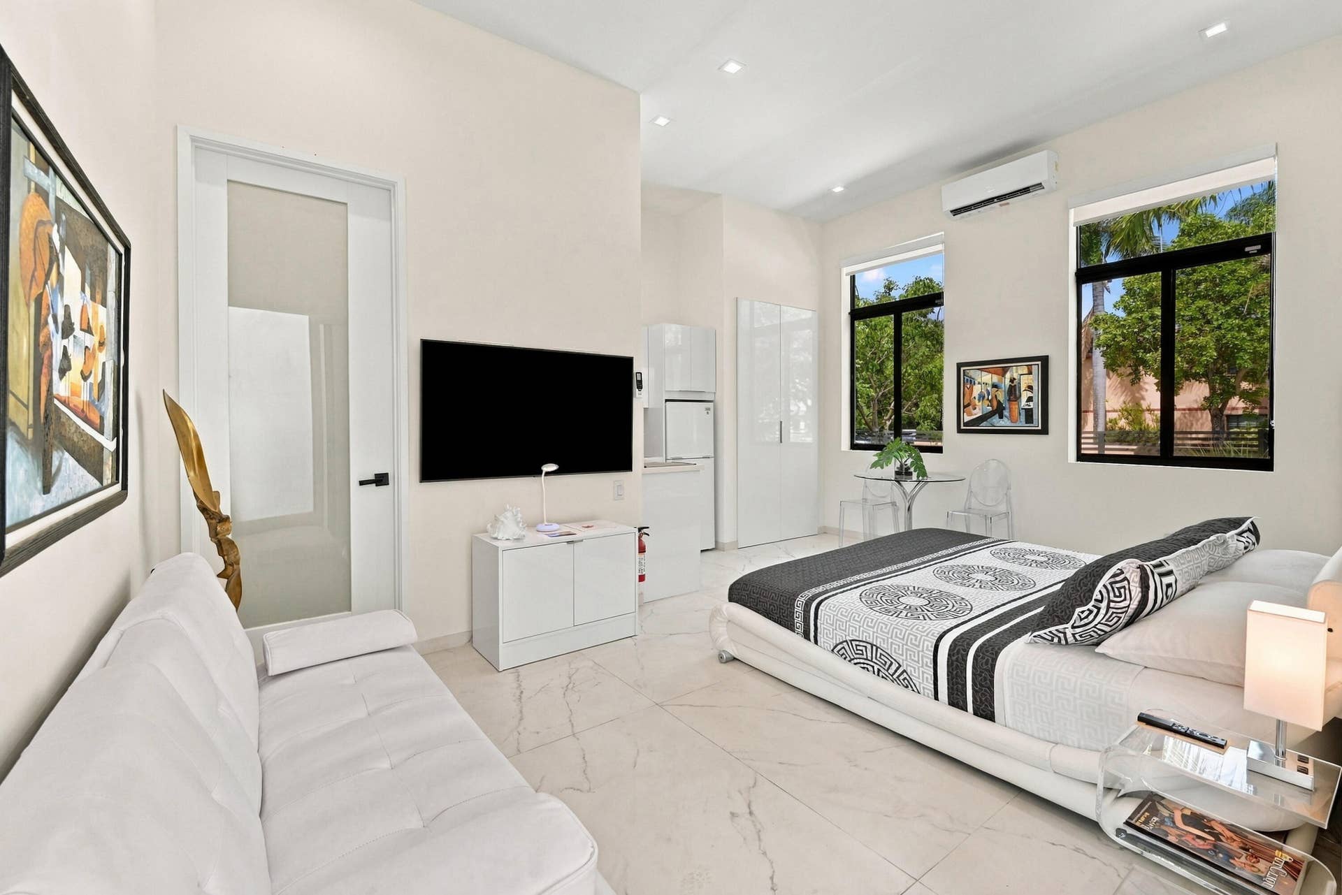 110 NE 16TH Place, Fort Lauderdale, FL 33305 Spacious living area featuring polished tile flooring, high ceilings, large windows, and a built-in air conditioning unit