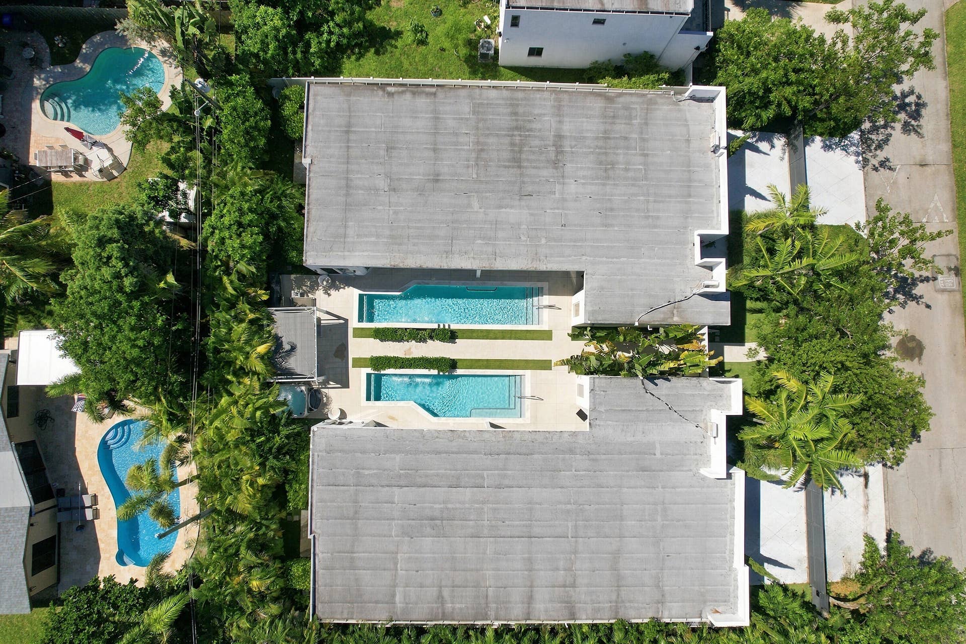 110 NE 16TH Place, Fort Lauderdale, FL 33305 Twin swimming pools with adjacent green spaces, surrounded by lush landscaping