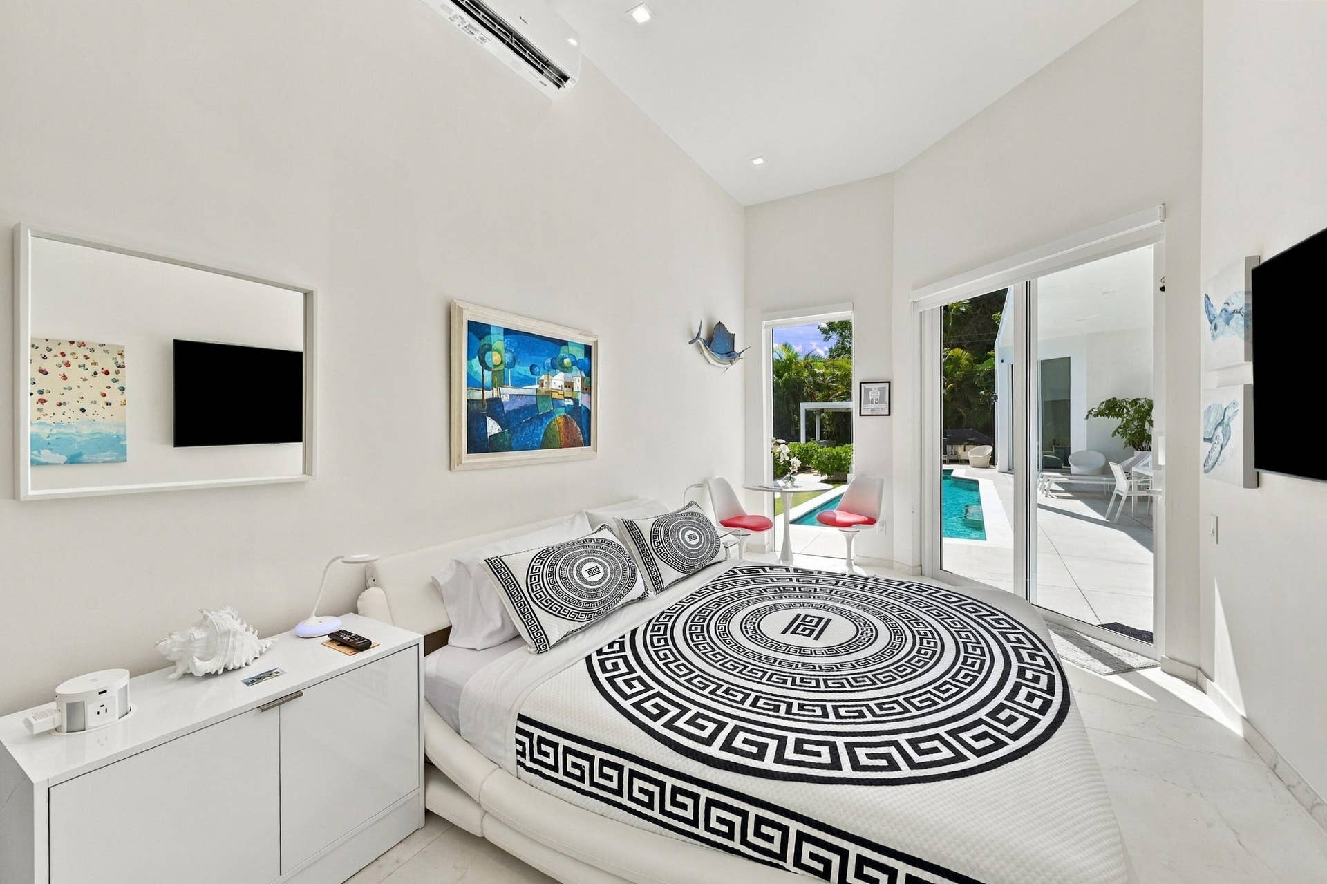 110 NE 16TH Place, Fort Lauderdale, FL 33305 Modern primary bedroom featuring floor-to-ceiling glass doors opening to outdoor spaces, recessed ceiling lighting, and white cabinetry with integrated storage