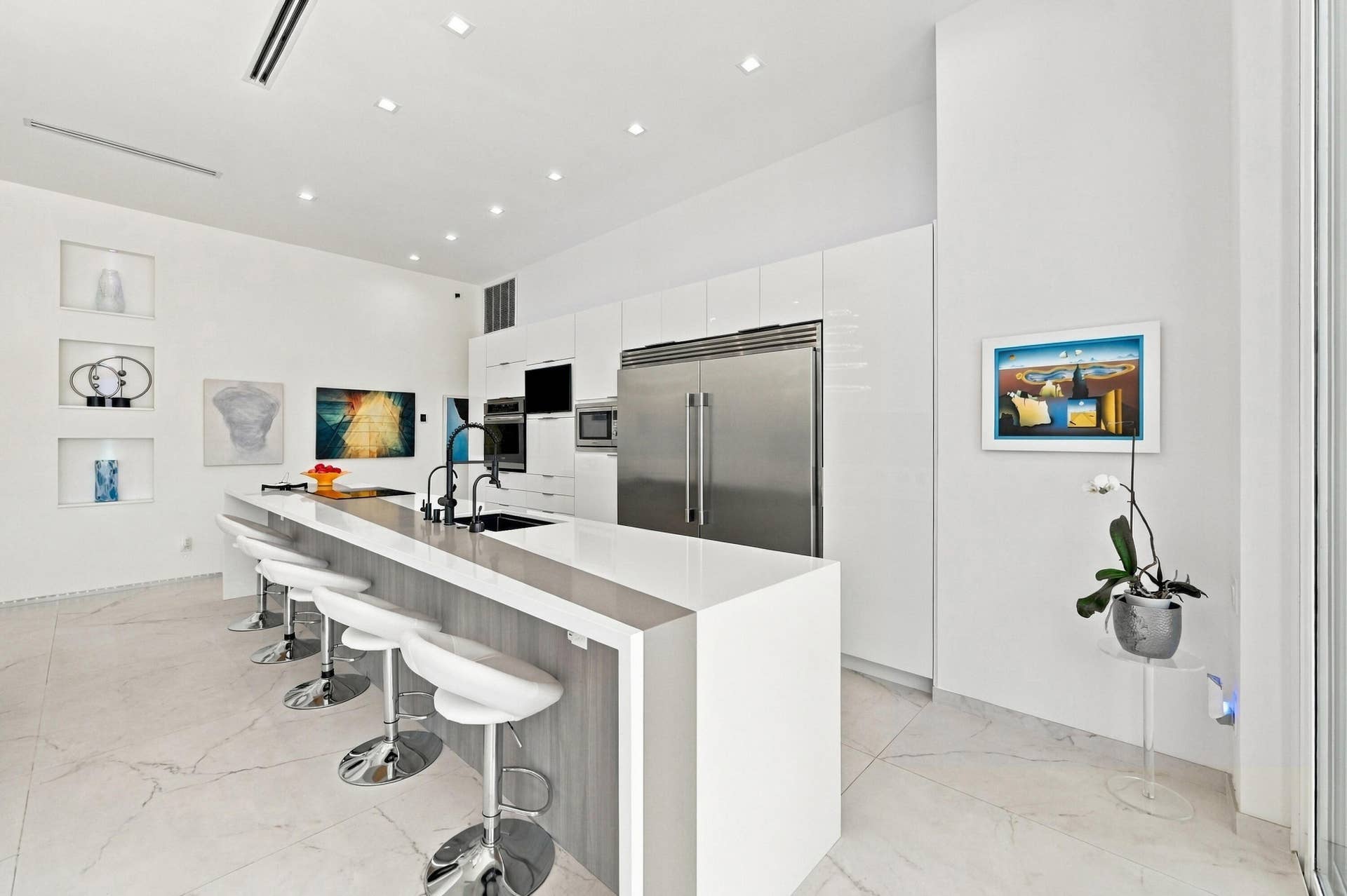 110 NE 16TH Place, Fort Lauderdale, FL 33305 Sleek kitchen featuring a large waterfall island, integrated stainless steel appliances, abundant white cabinetry, and recessed ceiling lighting