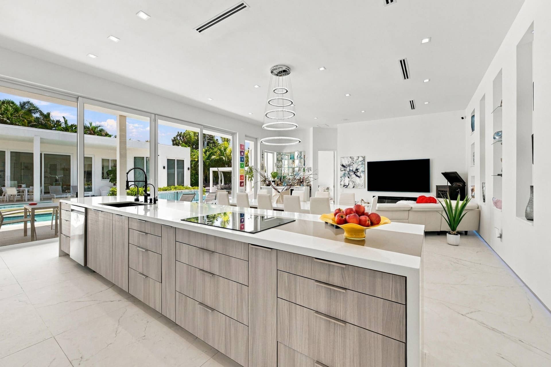 110 NE 16TH Place, Fort Lauderdale, FL 33305 Gourmet kitchen island with integrated cooktop and sink, white countertop, and wood-finish cabinetry