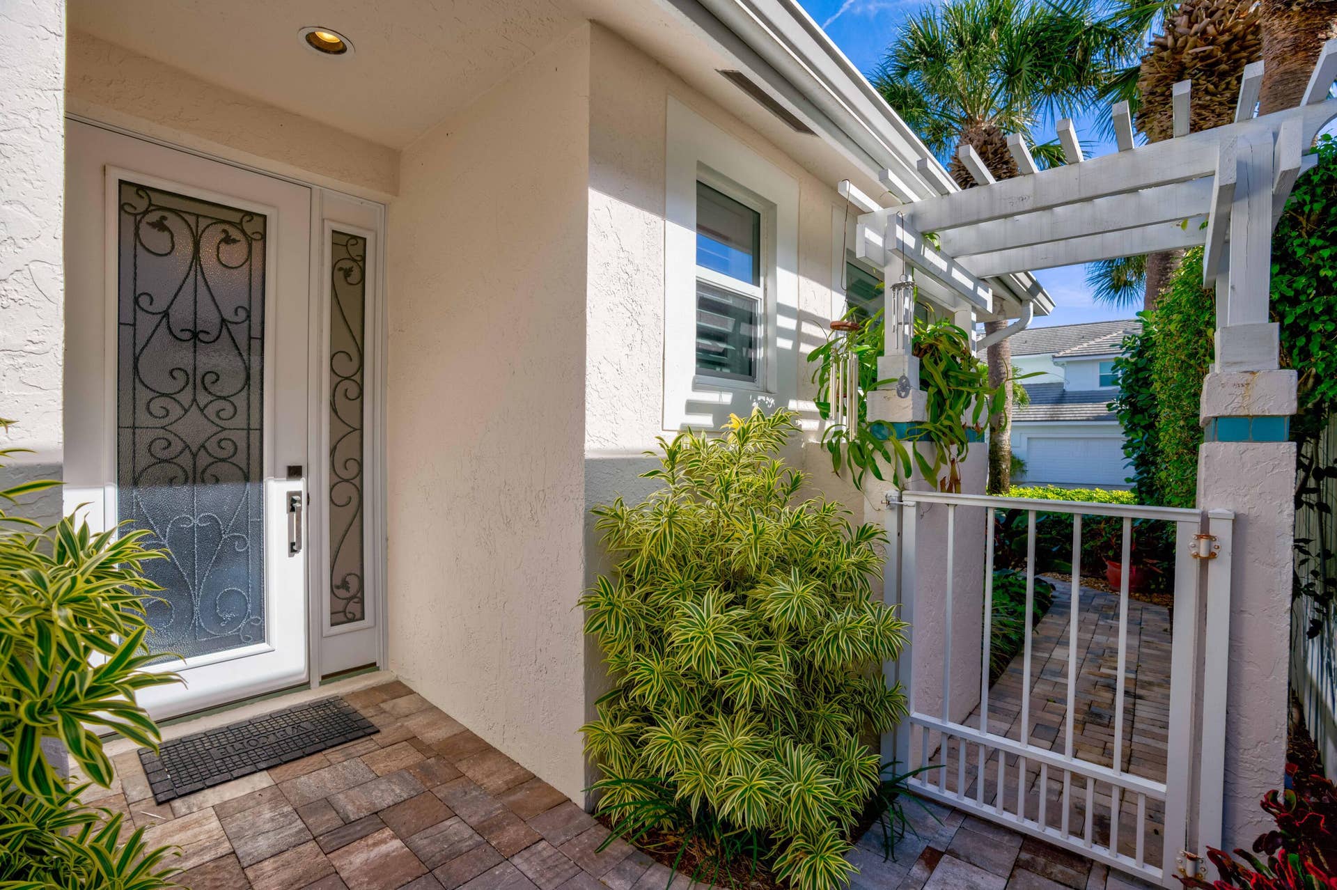 2043 Staysail Lane, Jupiter, Jupiter, FL 33477 Entryway featuring an ornate glass-paneled door, recessed lighting, paver walkway, white pergola, and privacy gate