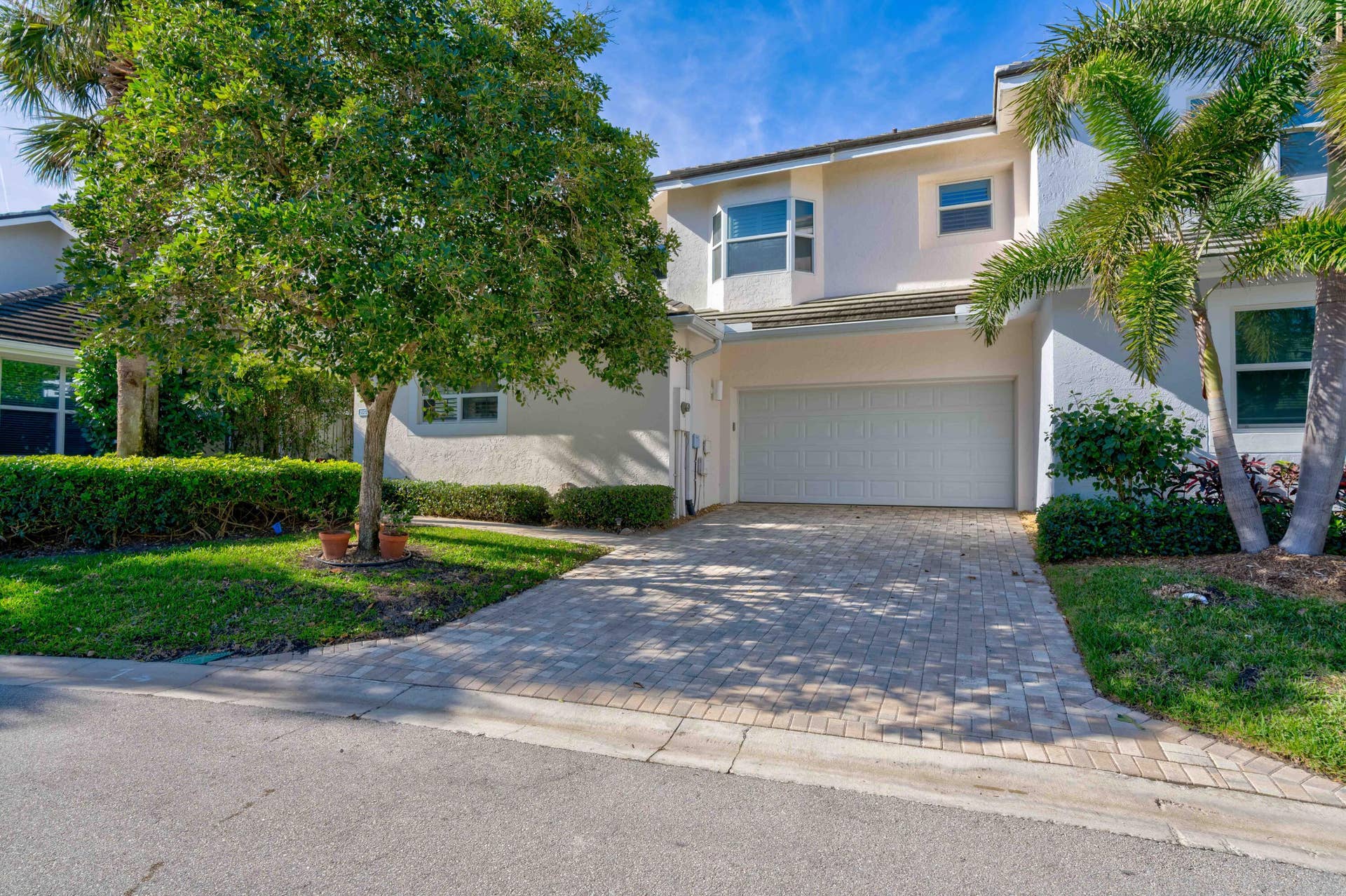 2043 Staysail Lane, Jupiter, Jupiter, FL 33477 Exterior featuring a paver driveway, an integrated garage, lush landscaping, and a bay window