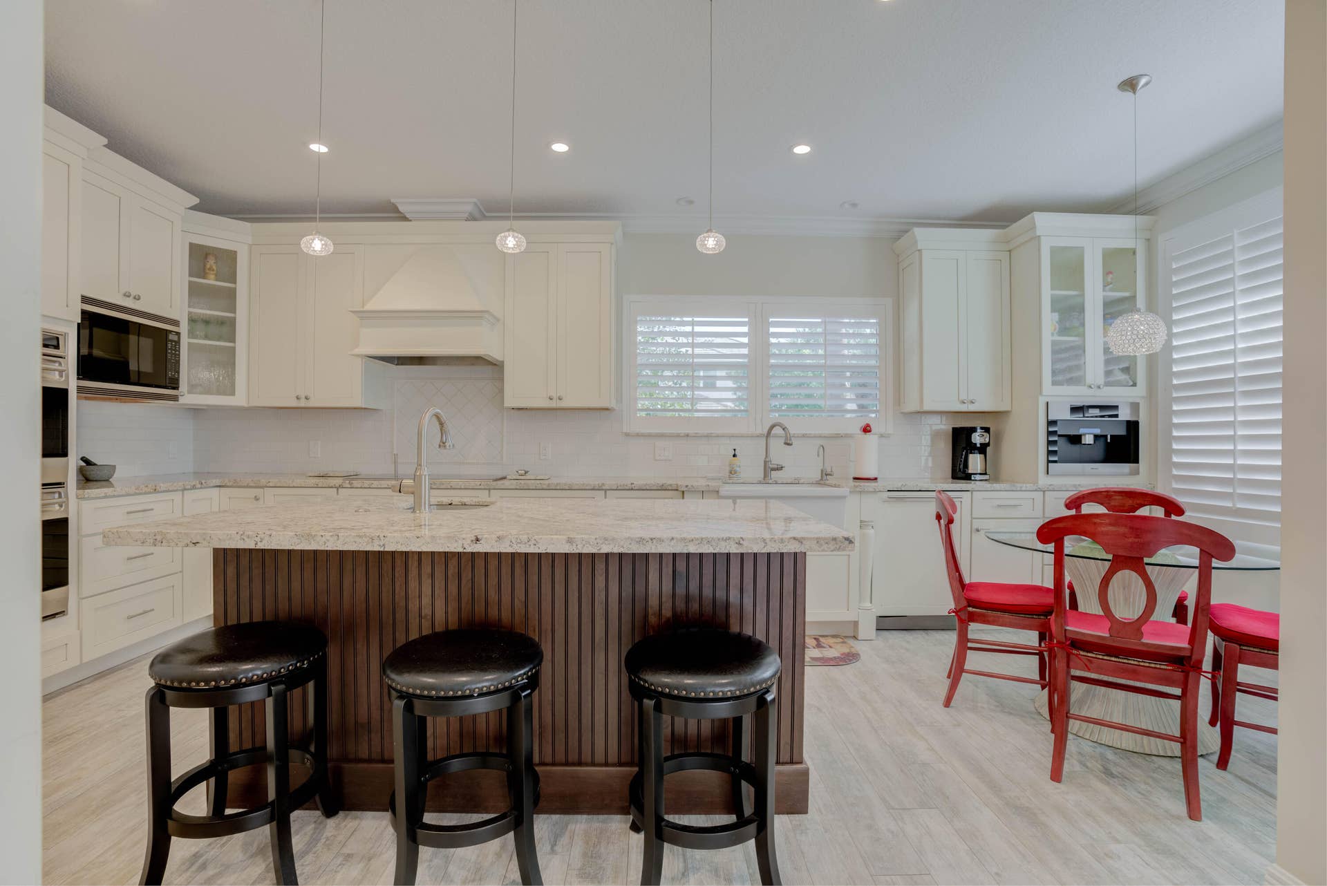 2043 Staysail Lane, Jupiter, Jupiter, FL 33477 White cabinetry with built-in appliances, a central island with a sink, light-toned countertop, wood-finish flooring, and pendant lighting