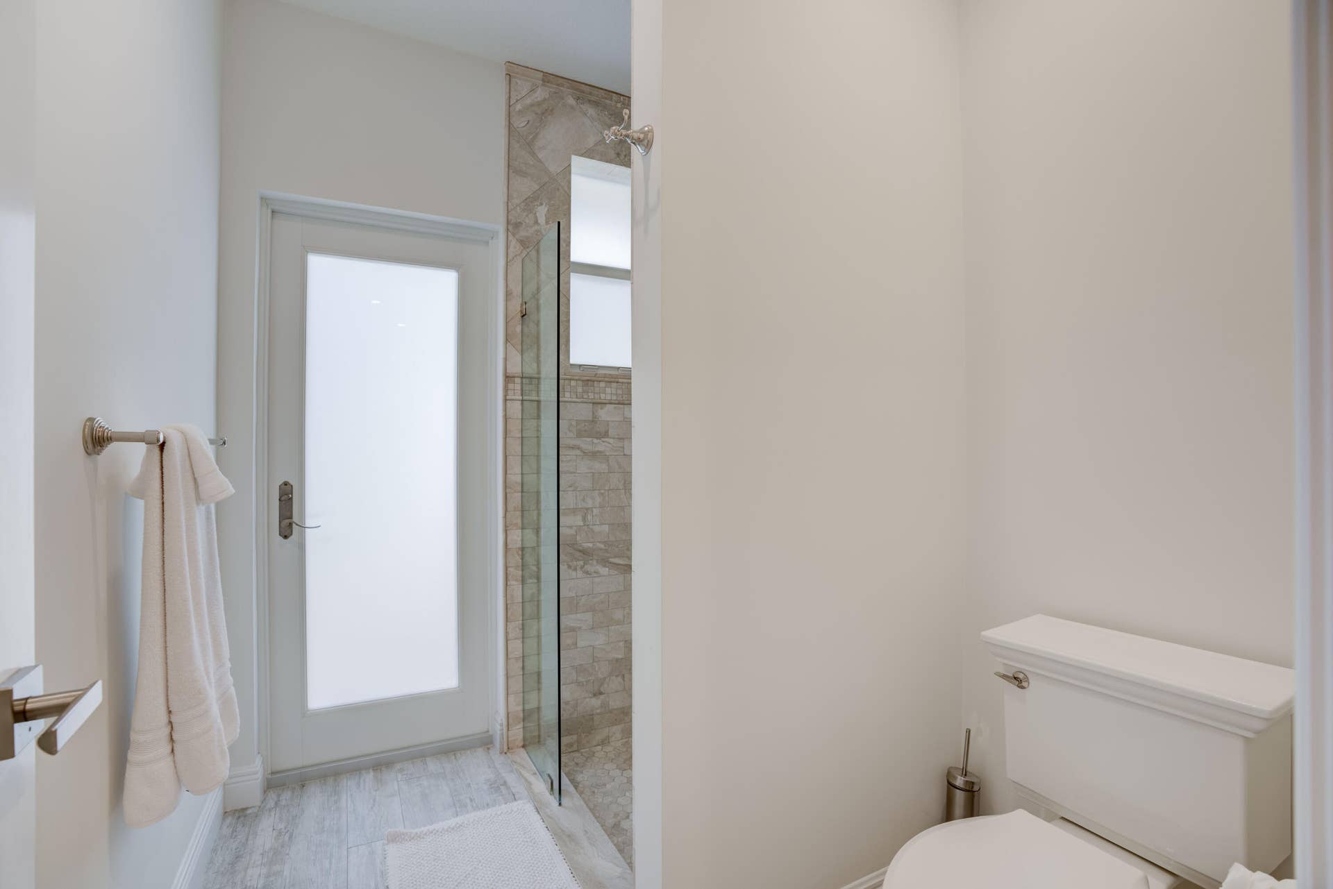 2043 Staysail Lane, Jupiter, Jupiter, FL 33477 Frosted glass panel door, shower with a glass enclosure, tiled shower surround, and wood-finish flooring