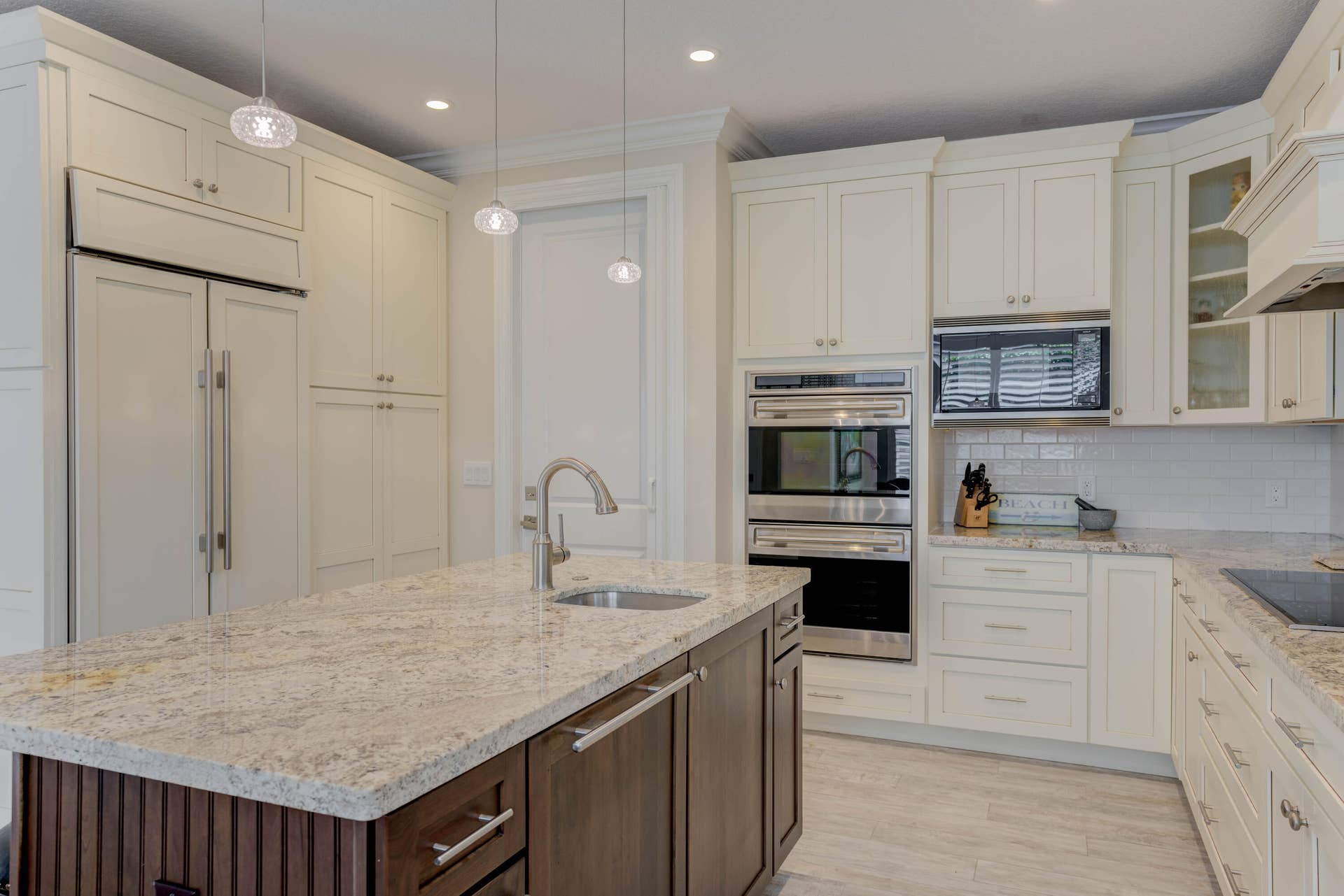 2043 Staysail Lane, Jupiter, Jupiter, FL 33477 Kitchen featuring white cabinetry, built-in stainless steel appliances, a center island with a sink, pendant lighting, and light-toned countertops