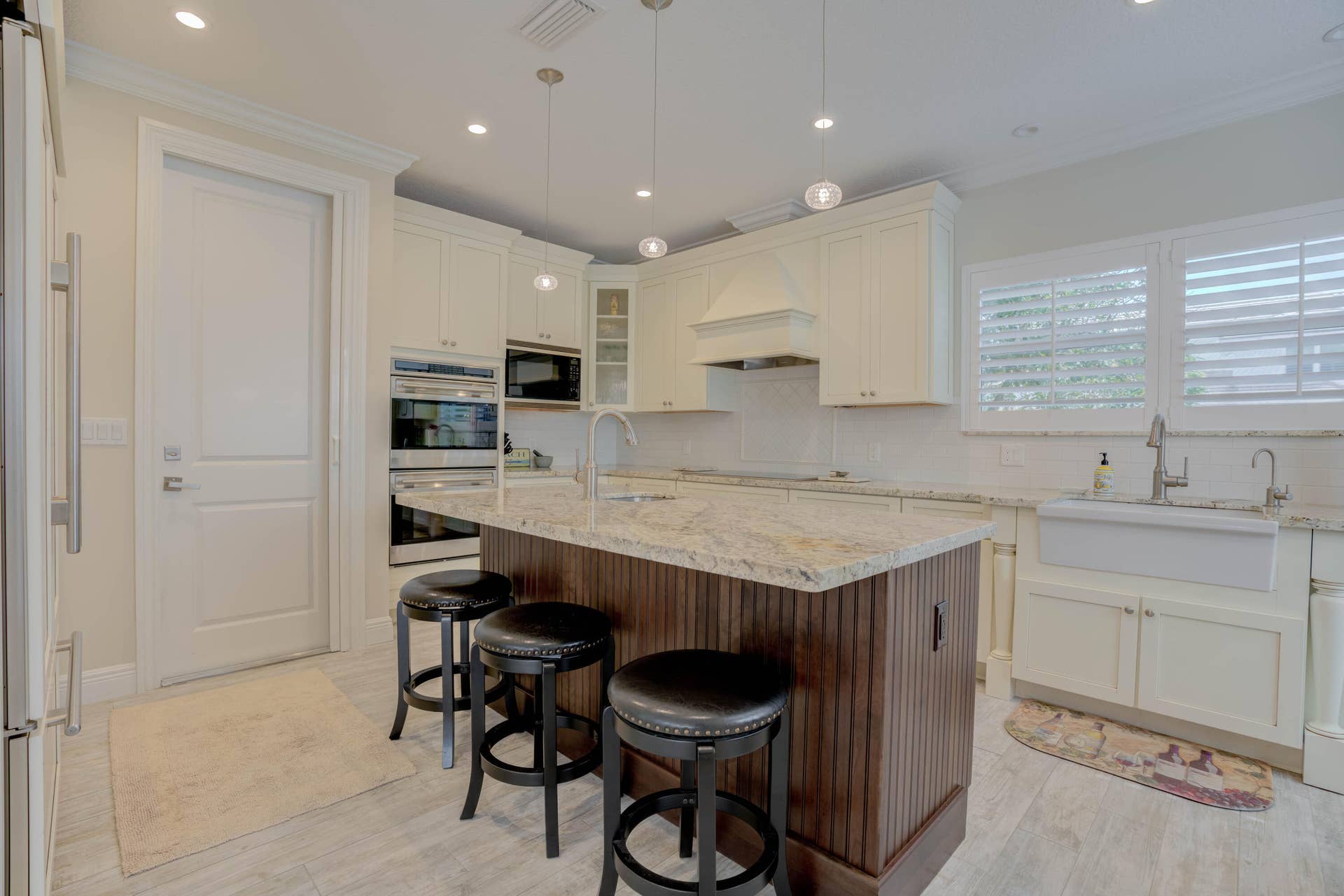 2043 Staysail Lane, Jupiter, Jupiter, FL 33477 Gourmet kitchen with double wall ovens, a large center island with a stone countertop, a farmhouse sink, and light wood-finish flooring