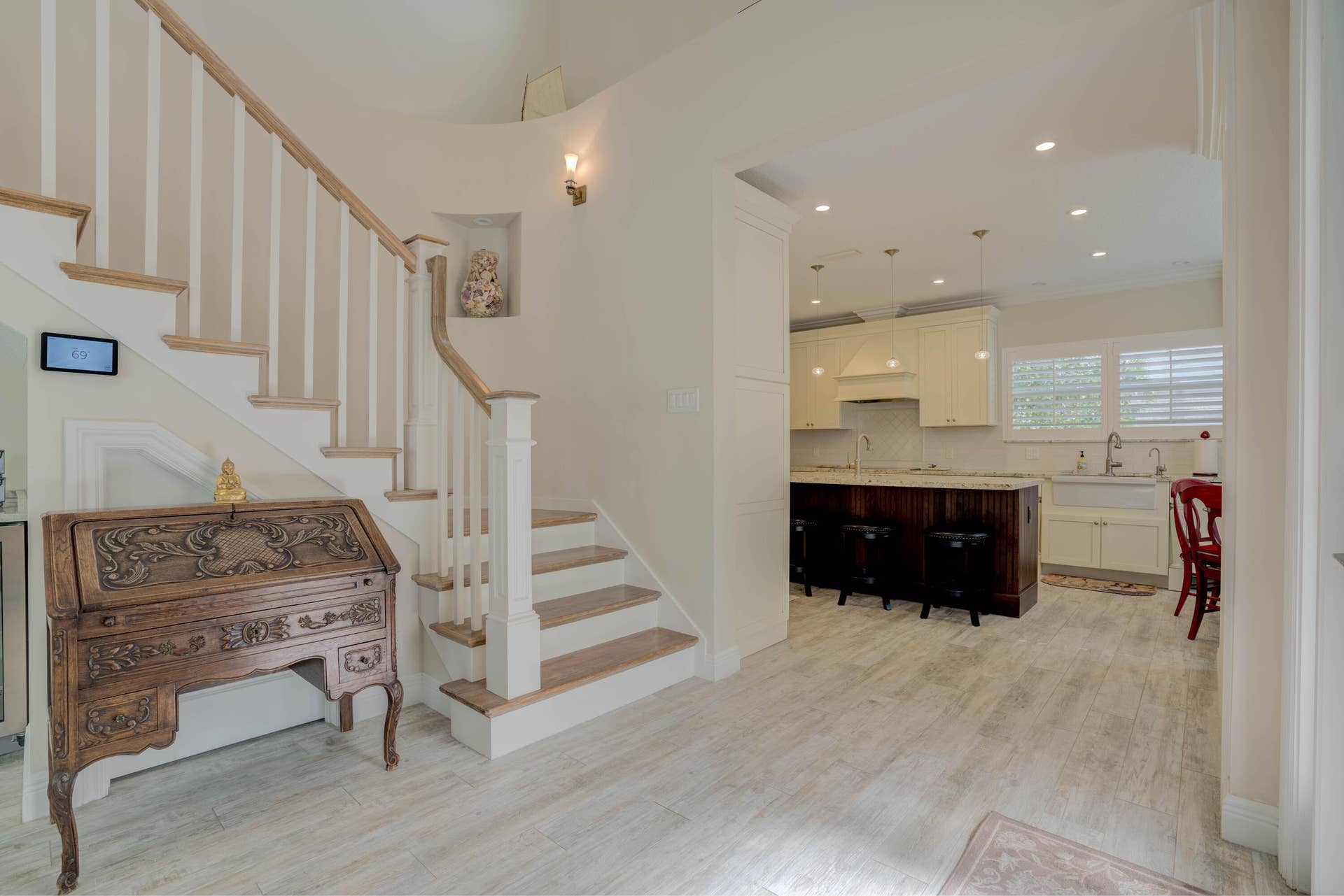 2043 Staysail Lane, Jupiter, Jupiter, FL 33477 Wood-finish flooring throughout, staircase with wood treads and white risers, kitchen with cream cabinetry, central island with seating, and recessed lighting