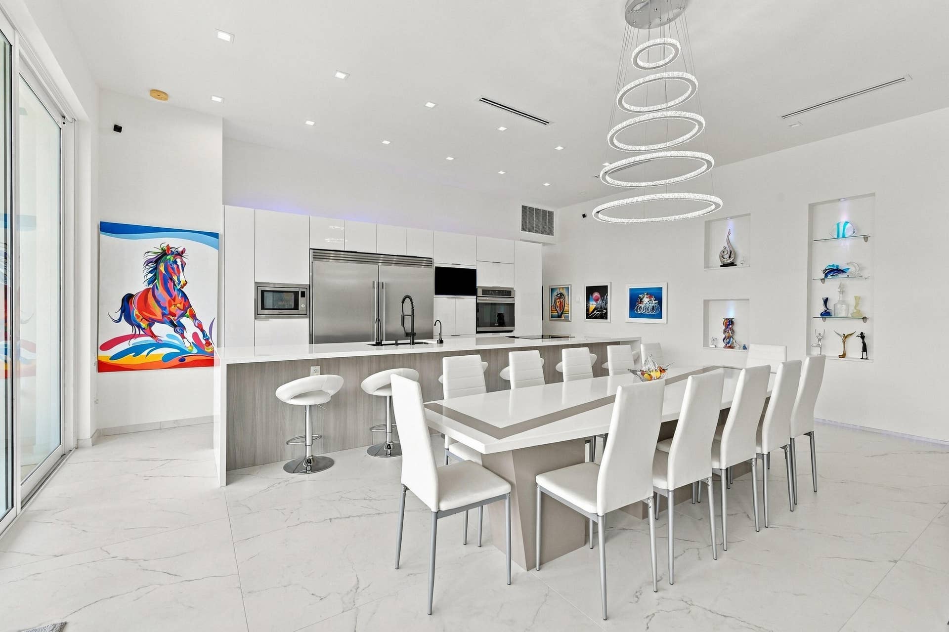 Kitchen and dining area featuring a modern chandelier, built-in display niches, stainless steel appliances, and white tile flooring