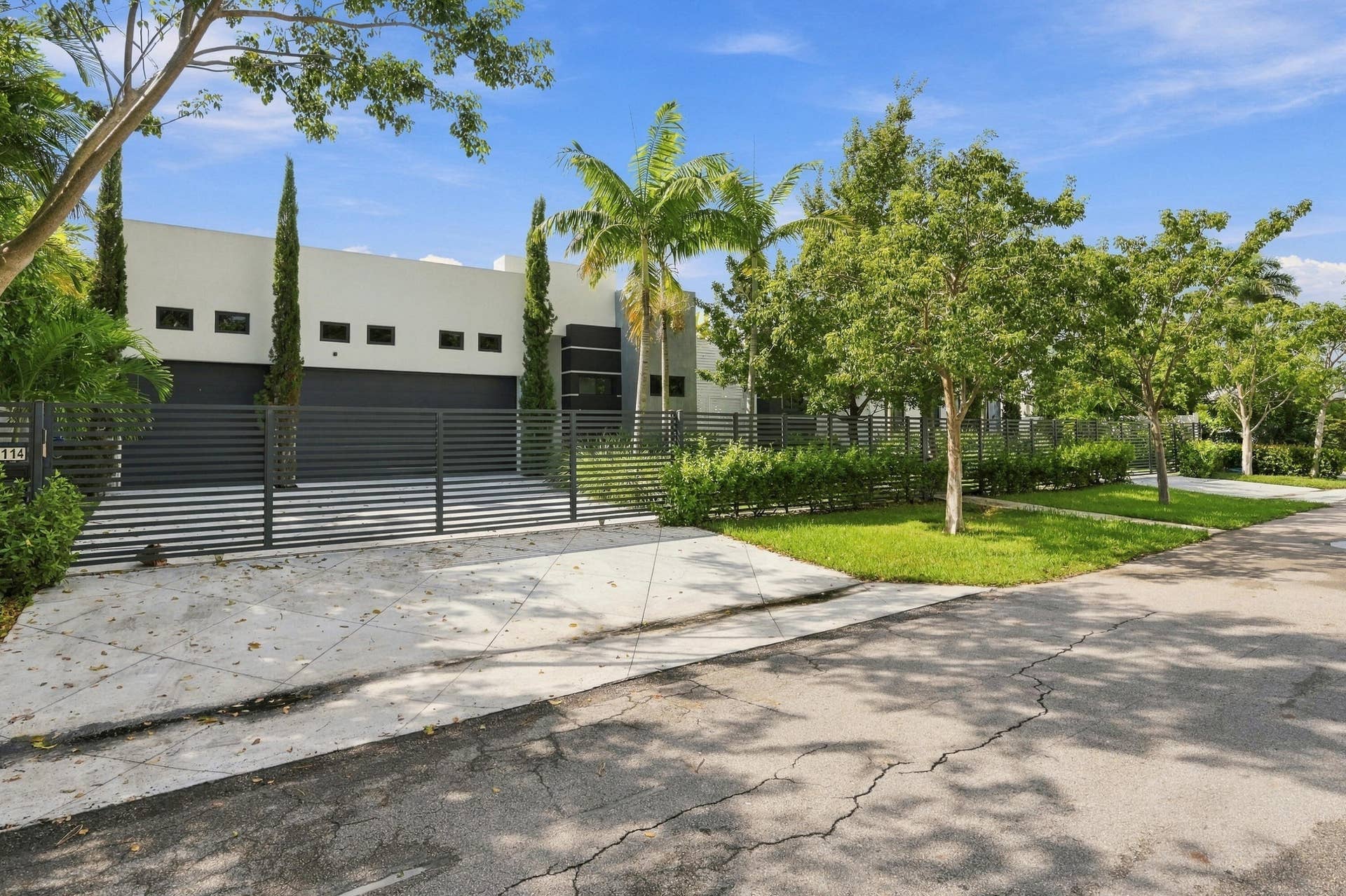 Modern exterior facade with a private gated entry and integrated garage doors