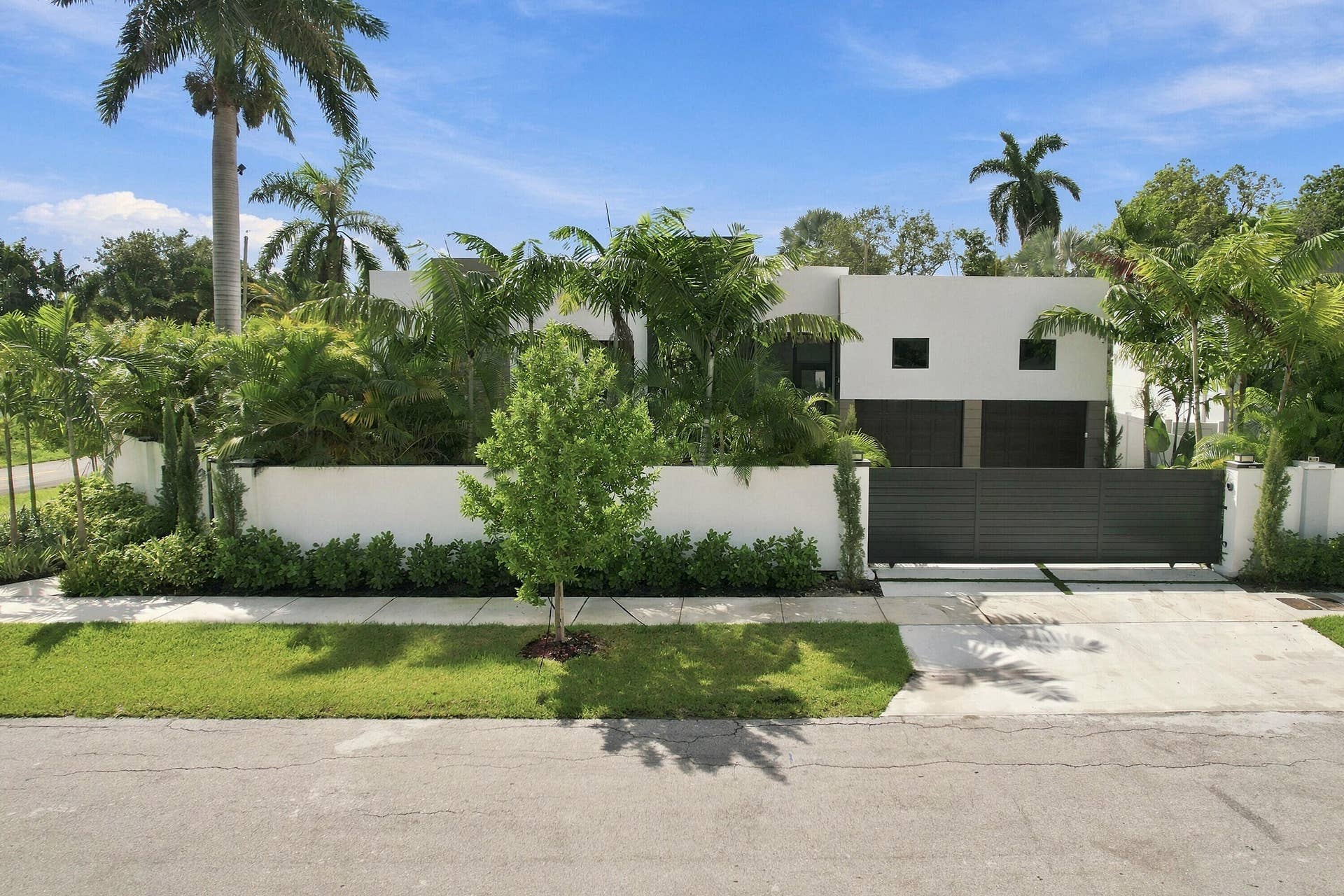 Modern exterior featuring a privacy wall, mature landscaping, and a secure entry gate