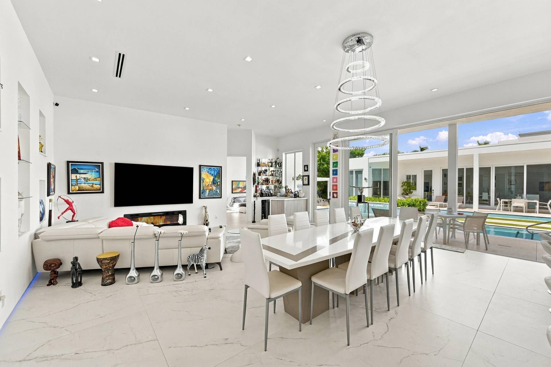 Open-concept living and dining area with white tile flooring, recessed lighting, and a modern linear fireplace