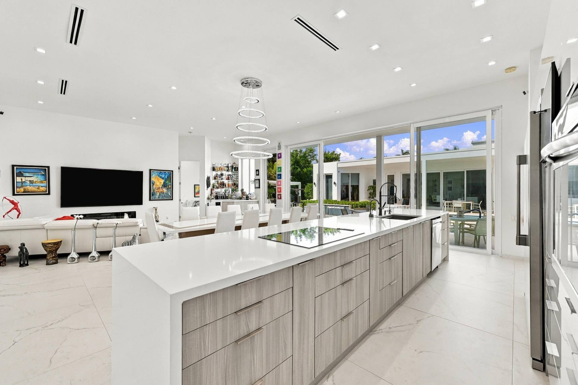 Spacious open-concept interior featuring large format tile flooring, a substantial kitchen island with a light-toned countertop, and modern wood-finish cabinetry