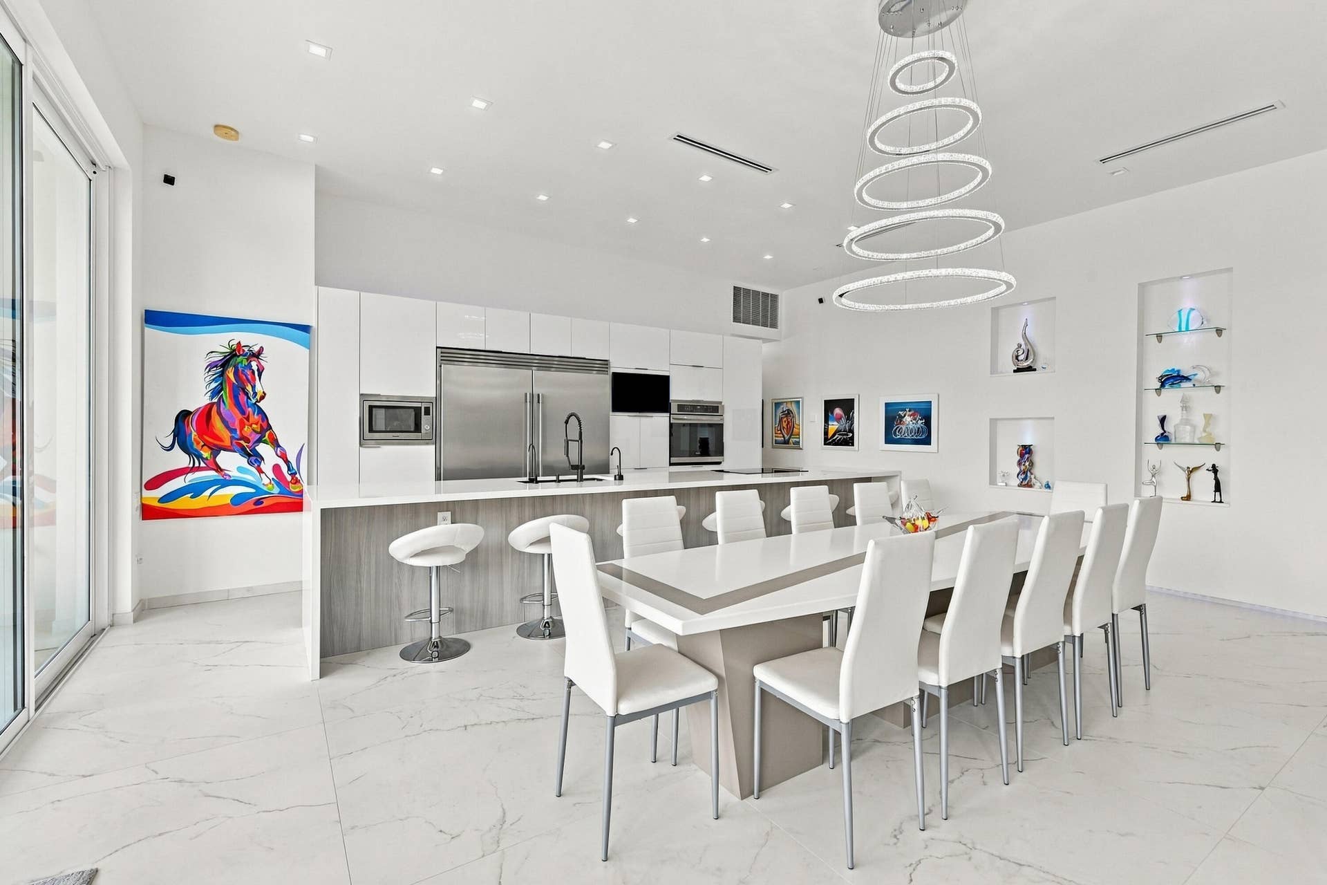 Sleek kitchen with white cabinetry and stainless steel appliances, featuring a large central island with seating