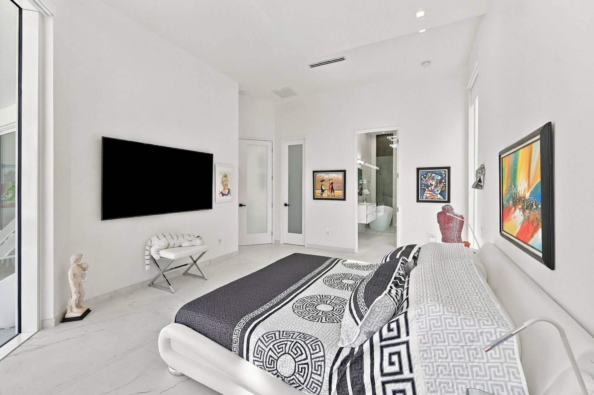 Recessed lighting, wall-mounted television, white tile flooring, white walls, and a white framed glass door