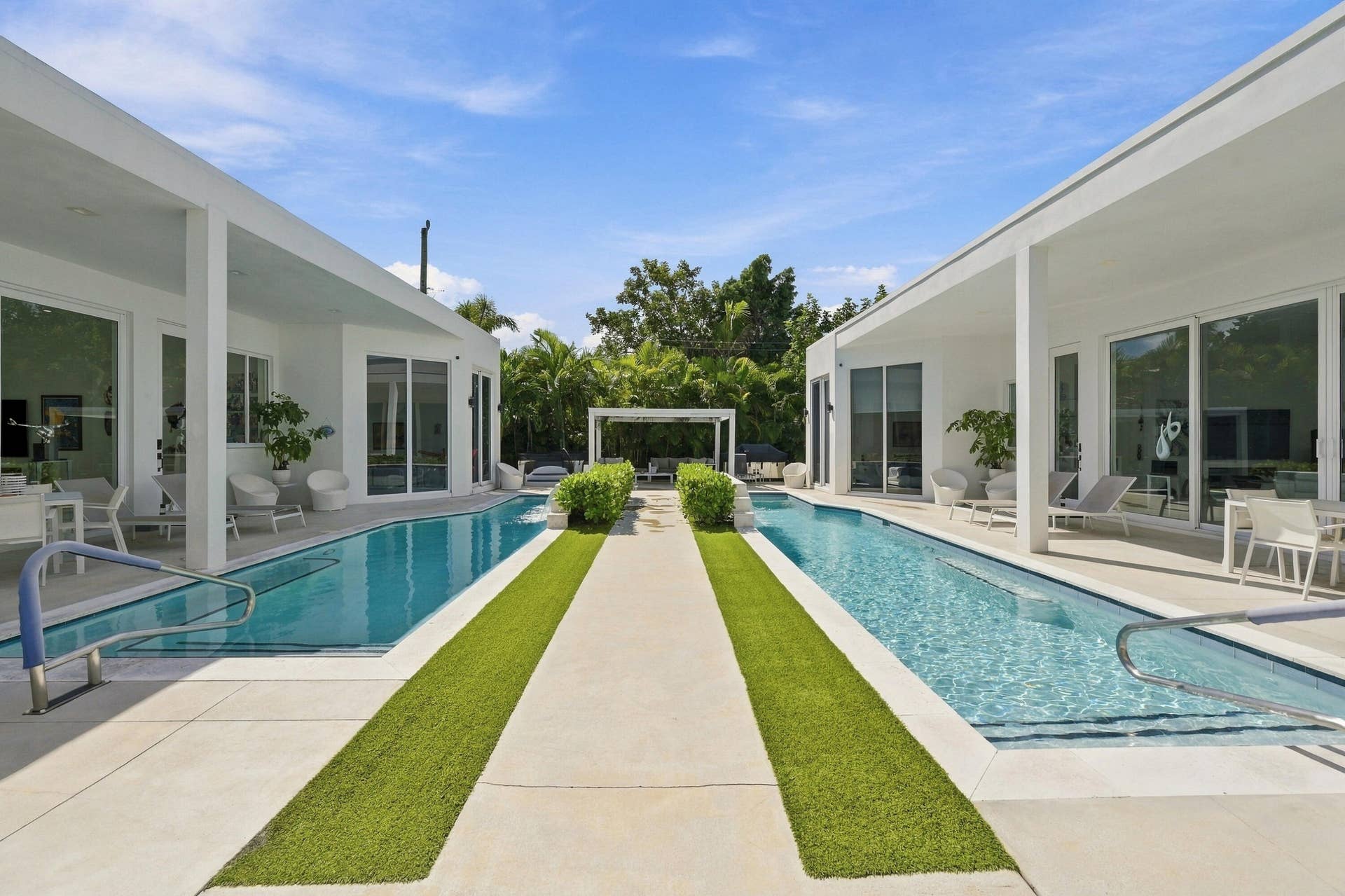 Two distinct pools framing a central walkway with artificial turf