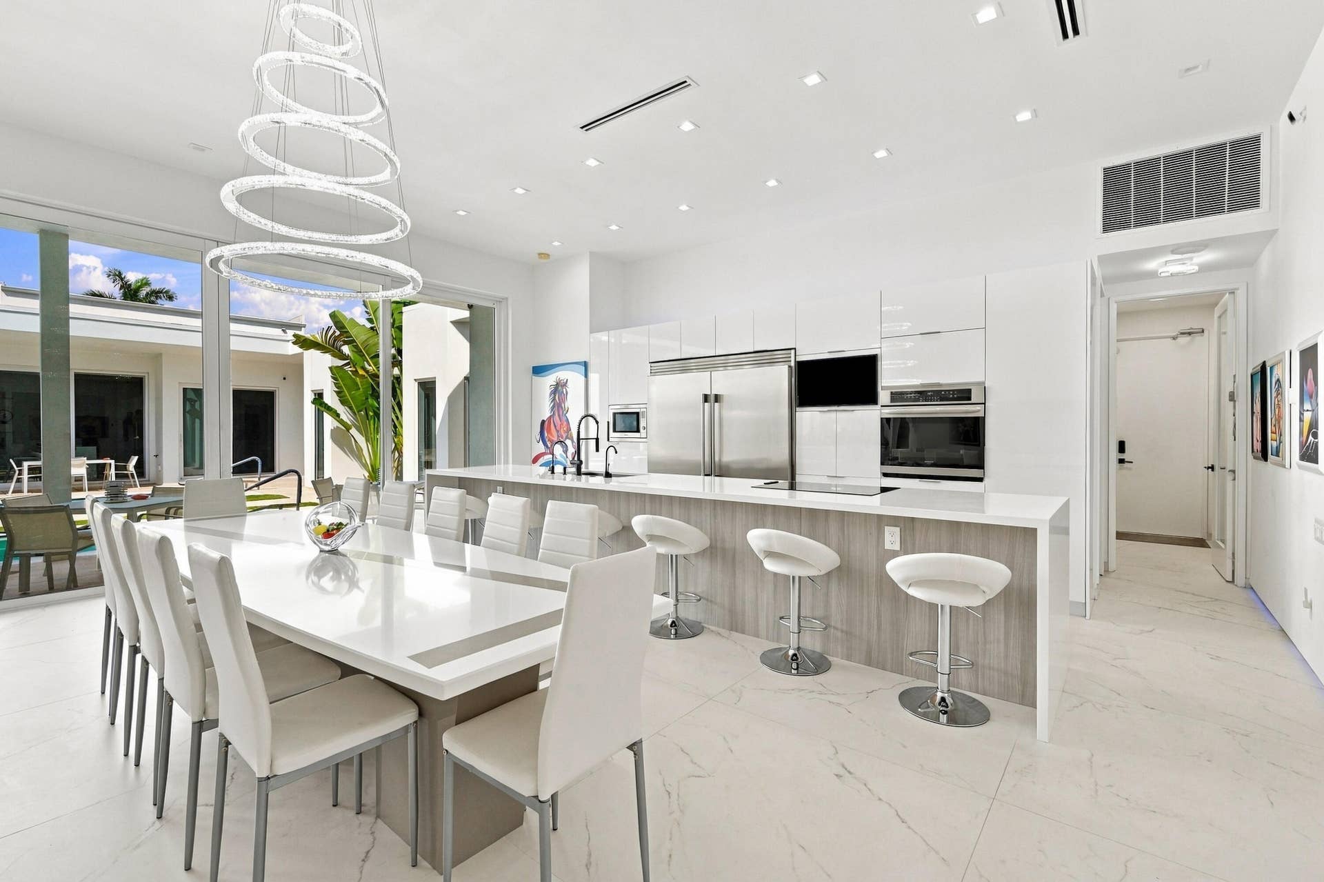 Modern kitchen featuring a large island with seating, stainless steel appliances, white cabinetry, and light-toned flooring