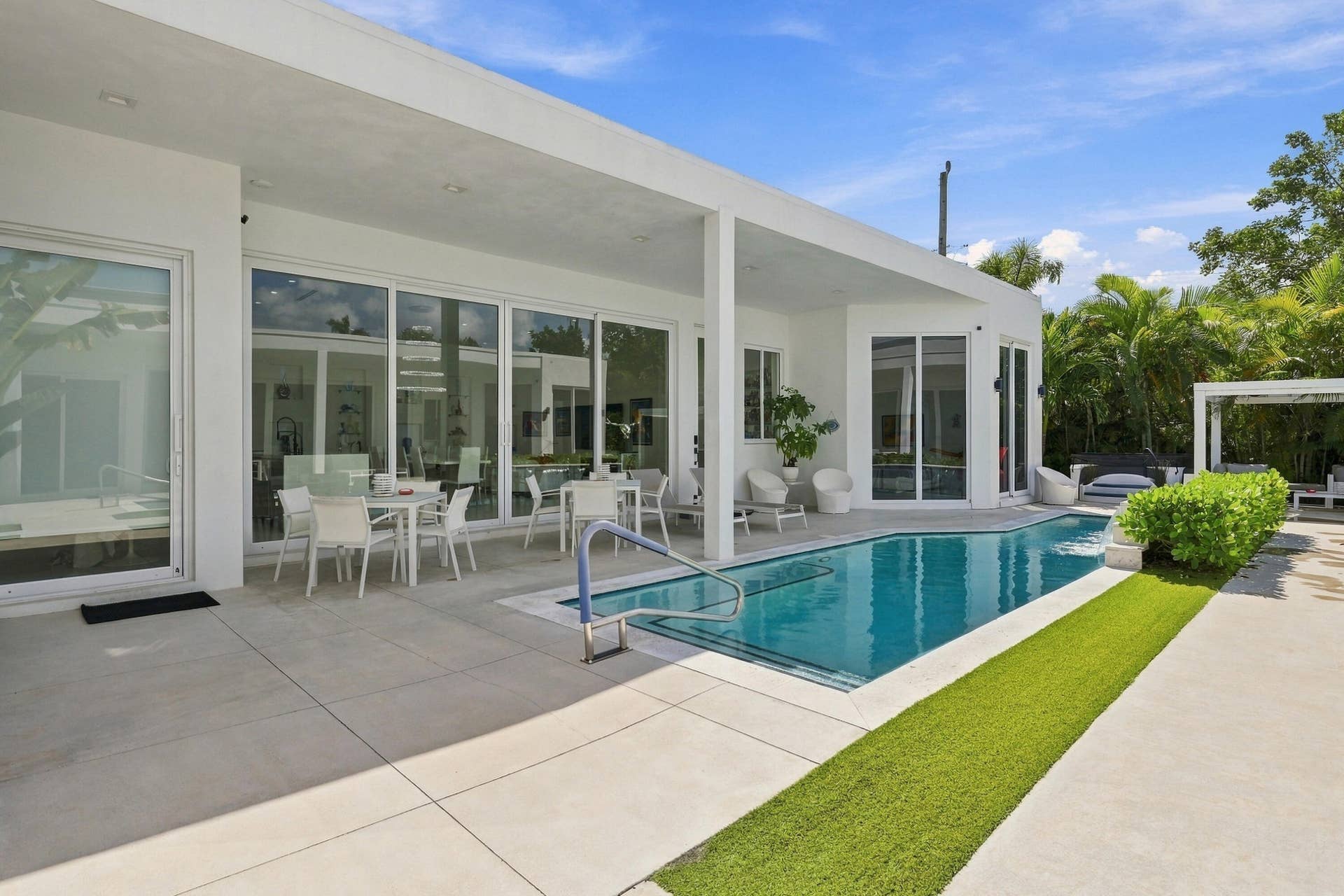 Modern exterior with an integrated swimming pool, expansive sliding glass doors, a large covered patio, and a separate pergola
