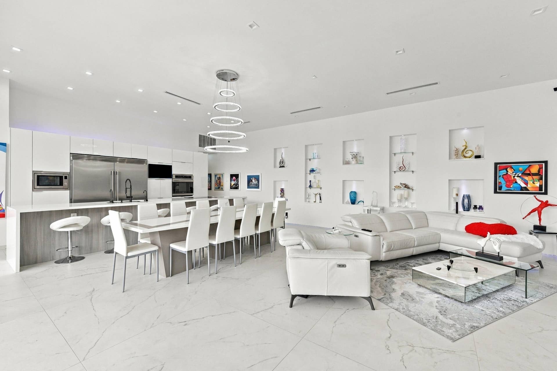 Recessed lighting throughout the ceiling, built-in display niches with accent lighting, and a modern tiered circular chandelier