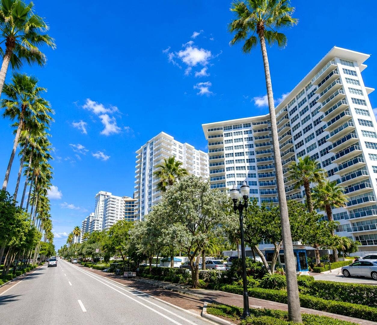 High-rise residential buildings featuring multiple balconies, palm trees, and lush landscaping
