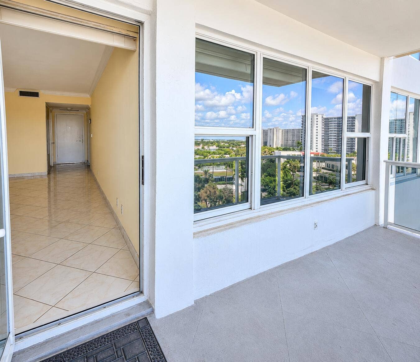 Expansive balcony with floor-to-ceiling windows, tile flooring, and metal railing