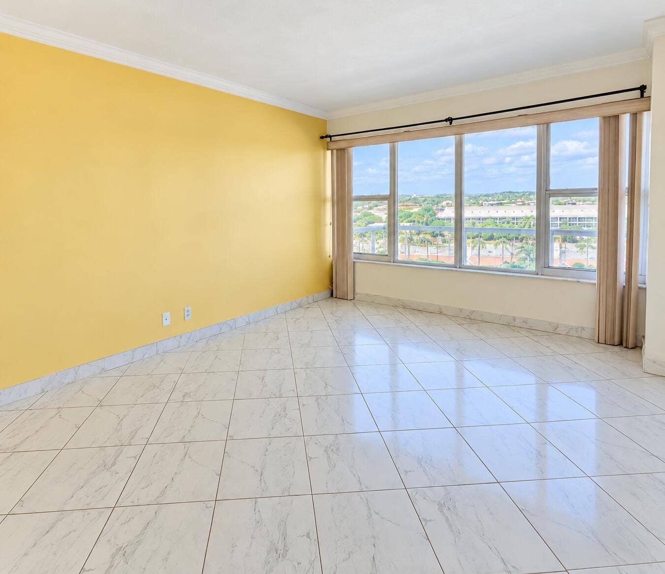 Polished white tile flooring, expansive window wall, crown molding, and a wide window ledge
