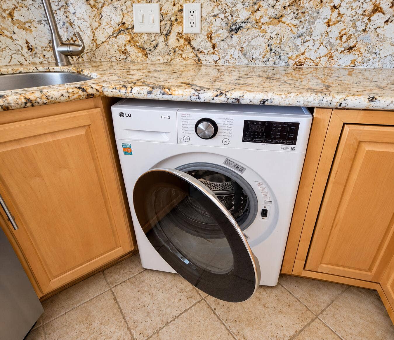 Built-in washer, granite countertop, stainless steel sink, gooseneck faucet, and light wood-finish cabinetry