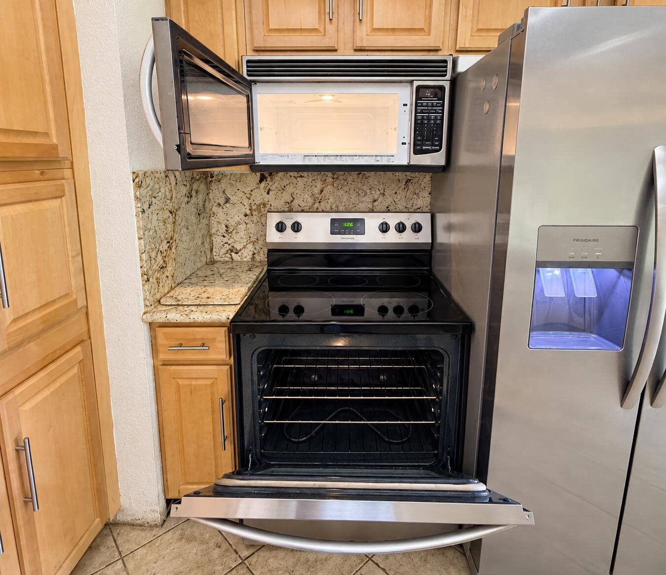 Stainless steel appliances, over-range microwave, electric range, and light wood-finish cabinetry