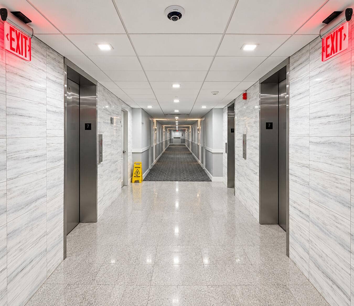 Polished terrazzo flooring, wall-mounted stainless steel elevators, and recessed ceiling lighting