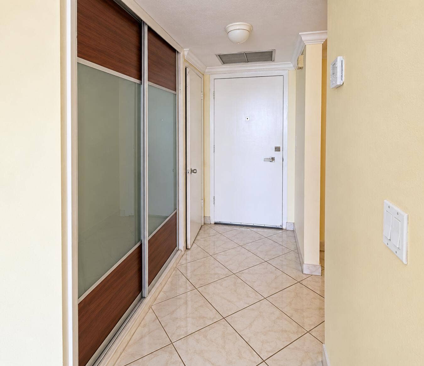 Tiled flooring, crown molding, and sliding closet doors with frosted glass panels and wood-finish accents