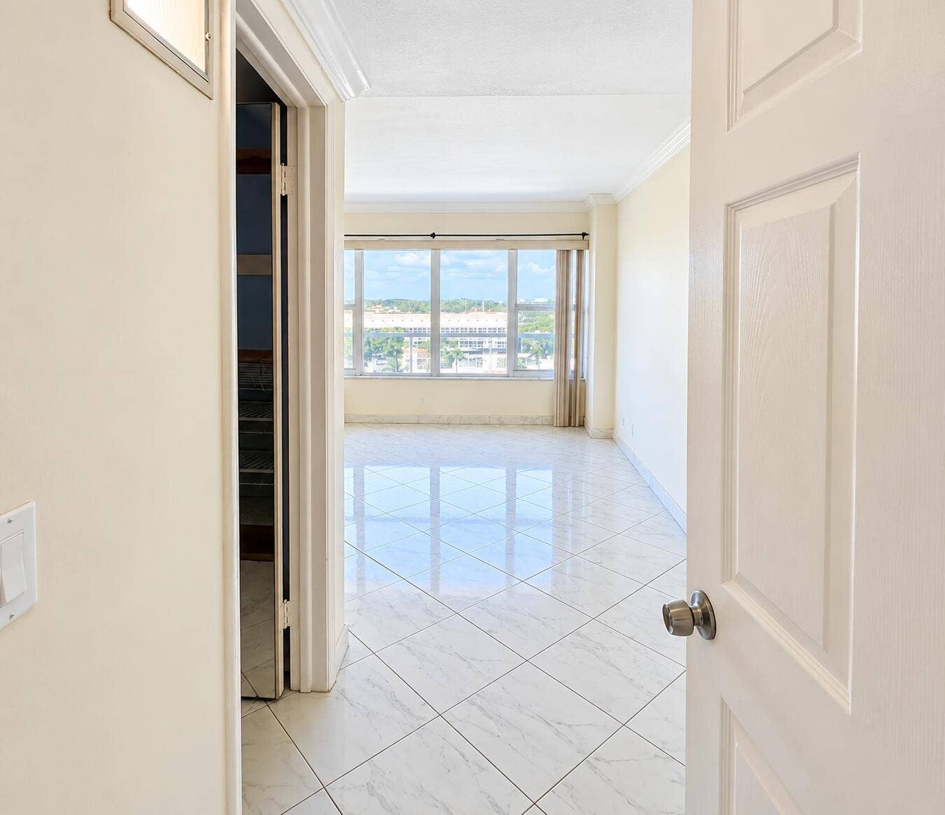 Glossy square tile flooring, expansive window, crown molding, and neutral wall tones