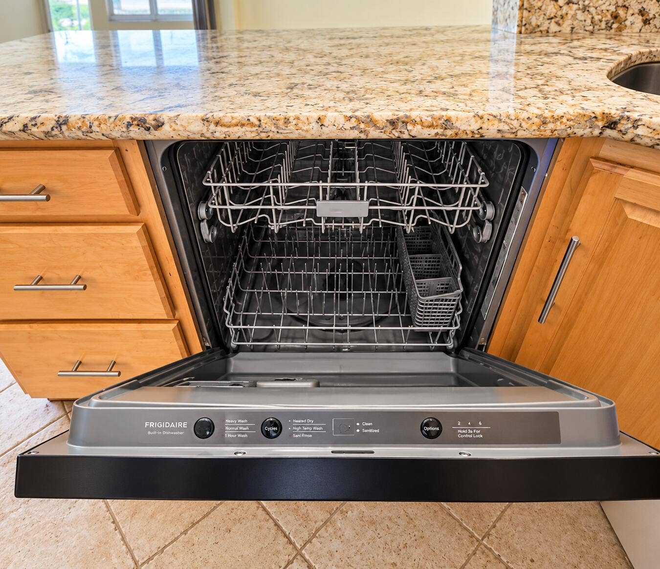 Built-in dishwasher with visible controls, integrated into custom wood cabinetry, featuring a granite countertop and a stainless steel sink