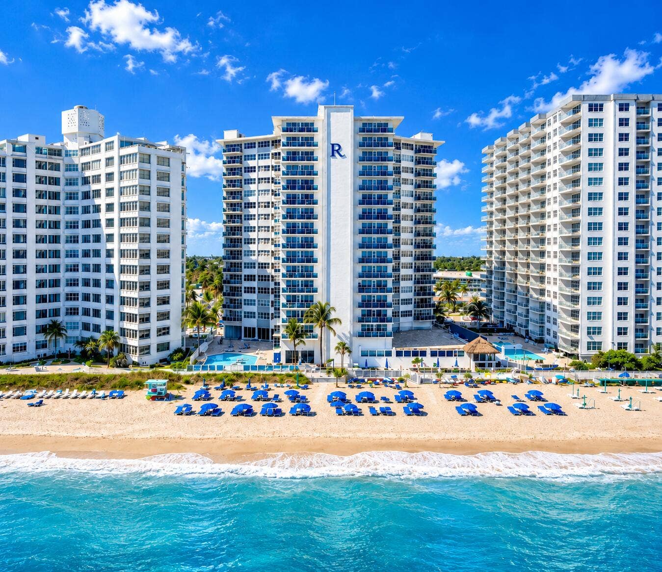 Beachfront high-rise buildings with expansive balconies and a ground-level pool deck