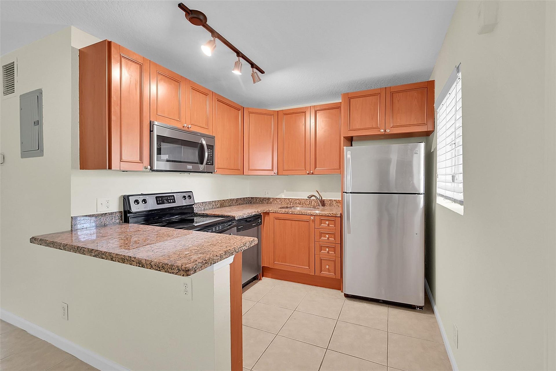 2655 NE 8th Avenue, #Apt 210, Wilton Manors, FL 33334 Kitchen featuring wood cabinetry, stainless steel appliances, granite-finish countertops, and tile flooring
