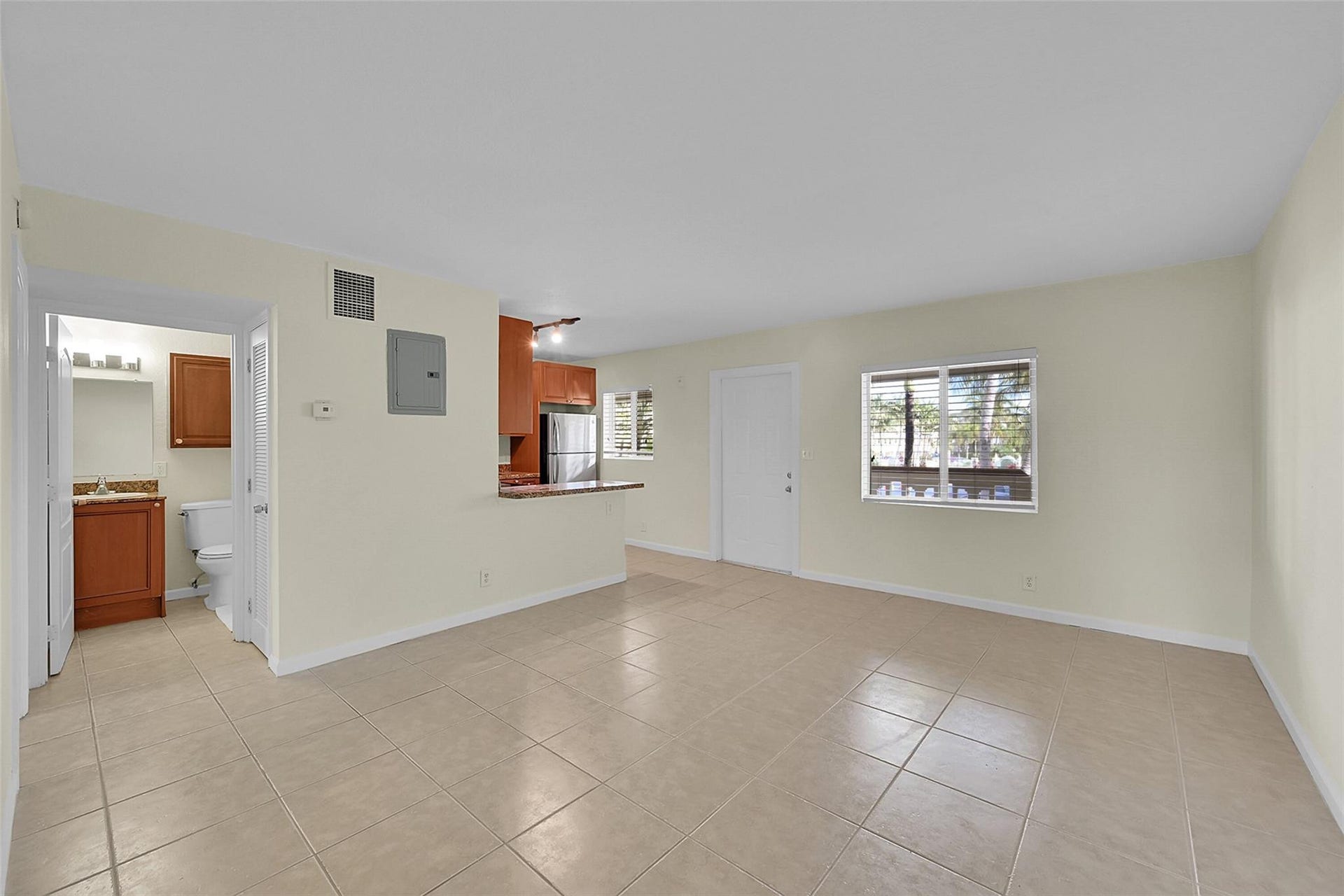 2655 NE 8th Avenue, #Apt 210, Wilton Manors, FL 33334 Tile flooring, recessed lighting, white interior door, window with blinds, and kitchen with brown cabinetry