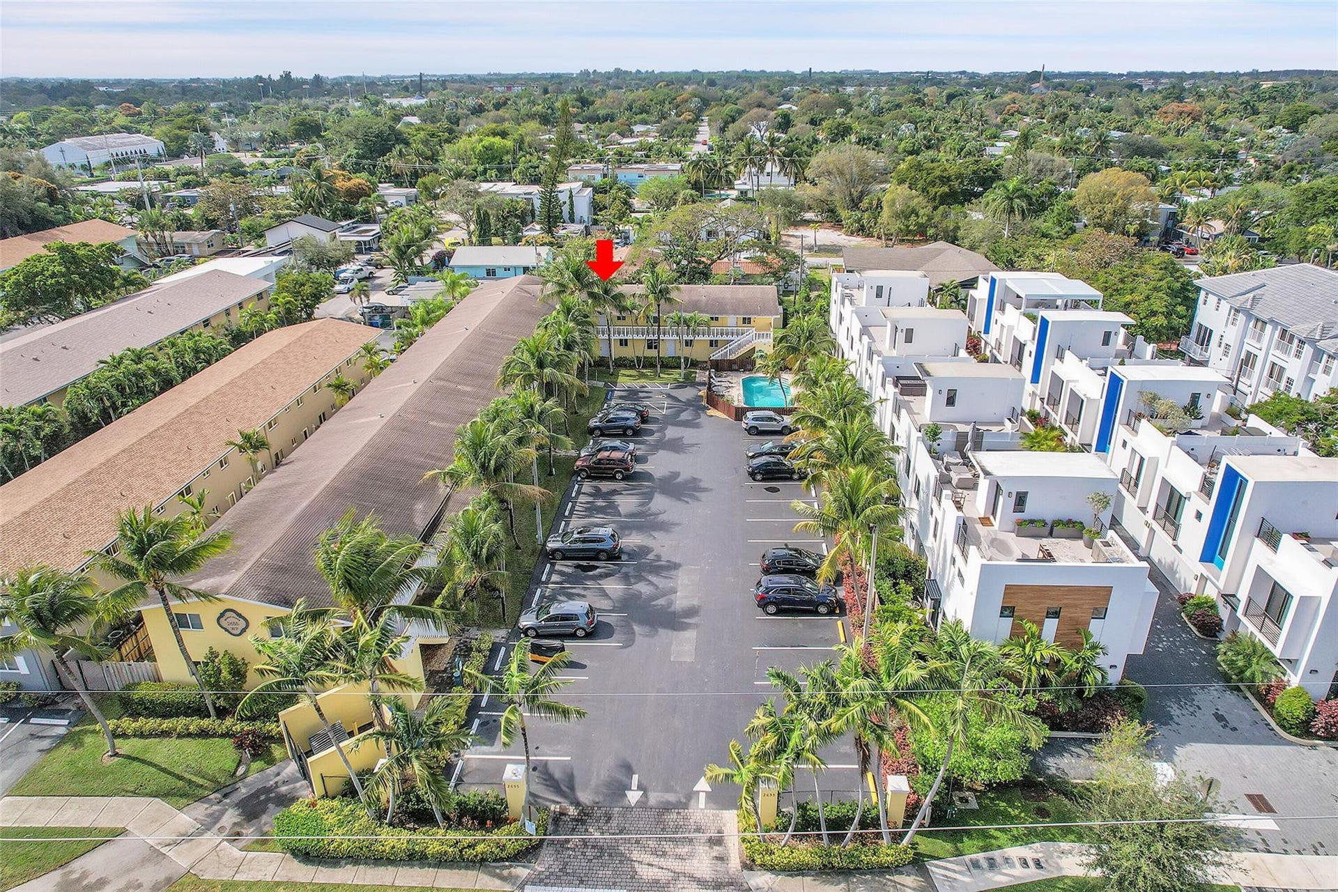 2655 NE 8th Avenue, #Apt 210, Wilton Manors, FL 33334 Gated community entrance with palm-lined parking, a shared pool, and contemporary building exteriors
