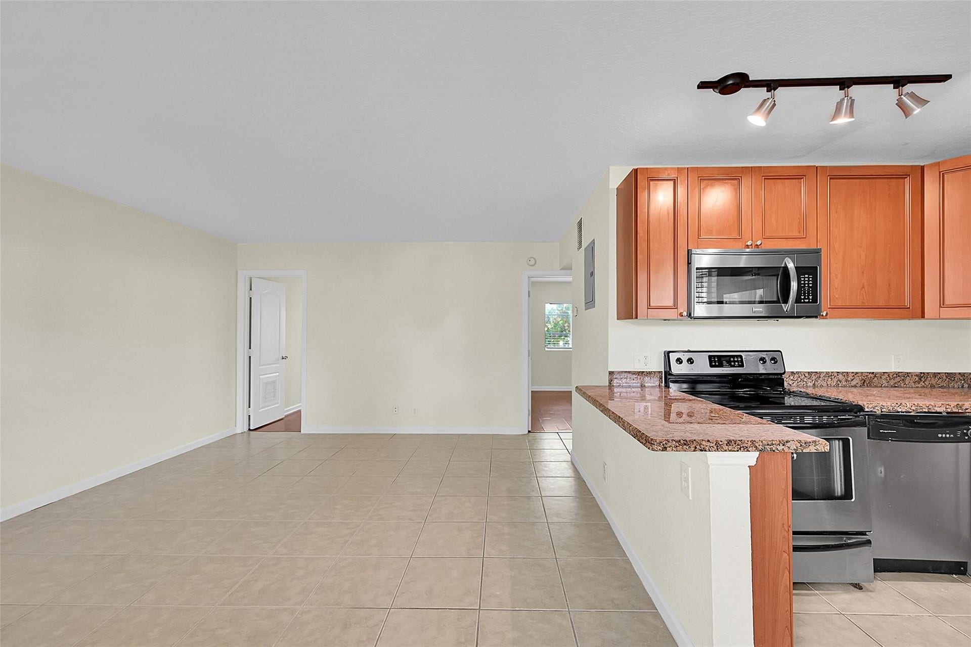 2655 NE 8th Avenue, #Apt 210, Wilton Manors, FL 33334 Kitchen featuring wood cabinetry, stainless steel microwave, stainless steel range, and stone countertops