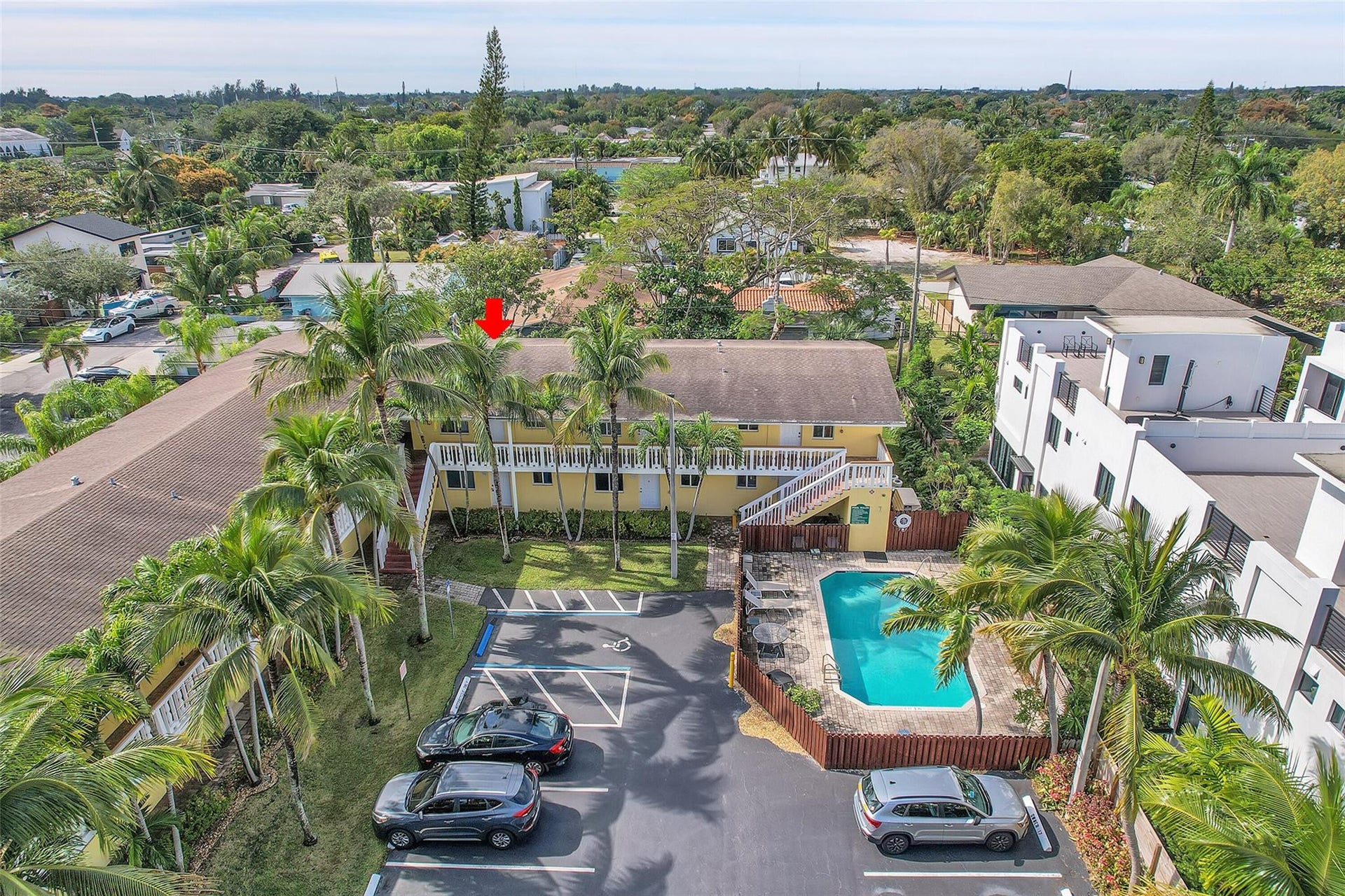 2655 NE 8th Avenue, #Apt 210, Wilton Manors, FL 33334 Multi-story residential building with exterior staircases, surrounded by mature palm trees