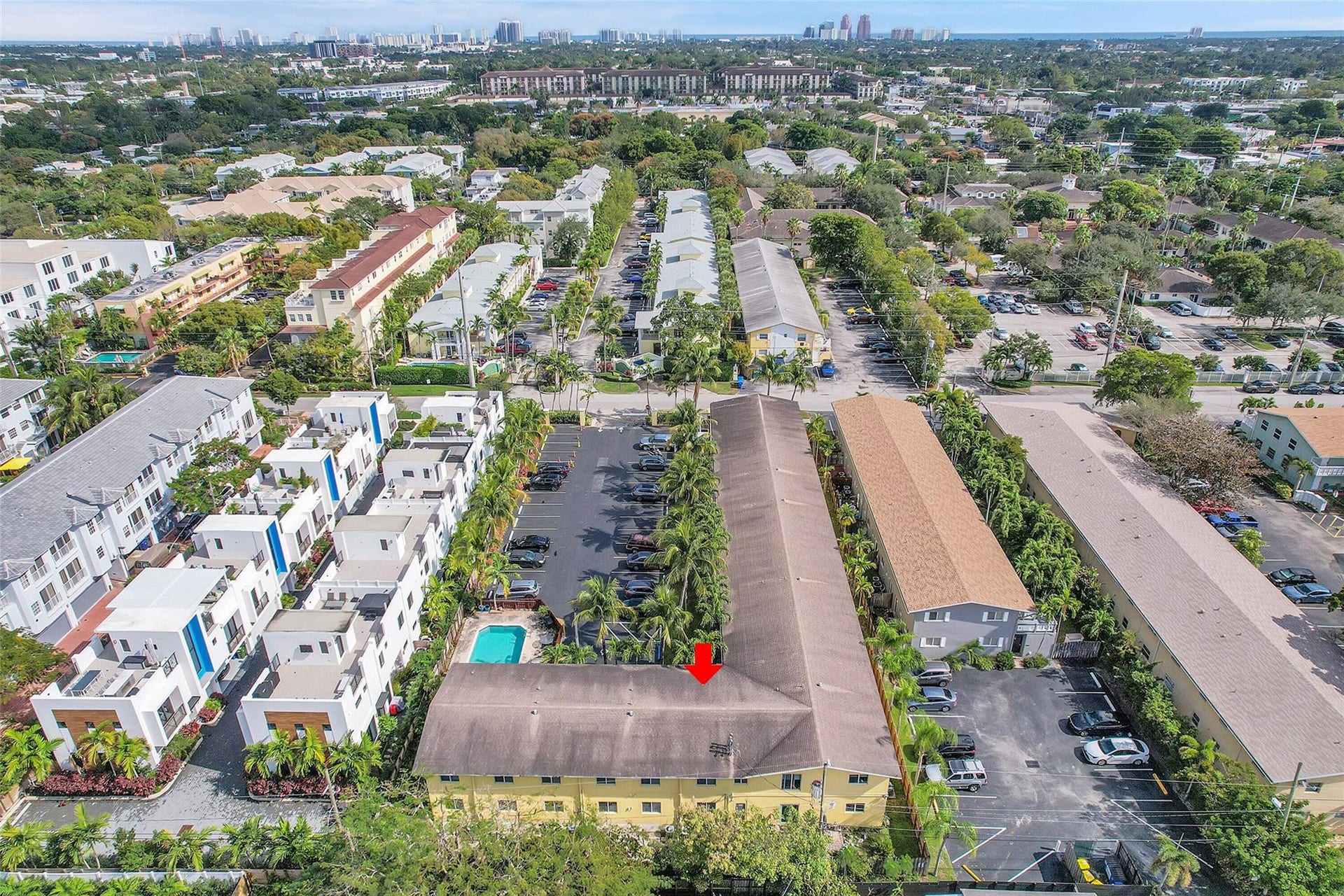 2655 NE 8th Avenue, #Apt 210, Wilton Manors, FL 33334 Aerial perspective showcasing a multi-unit property with a central courtyard pool, surrounding parking areas, and mature landscaping