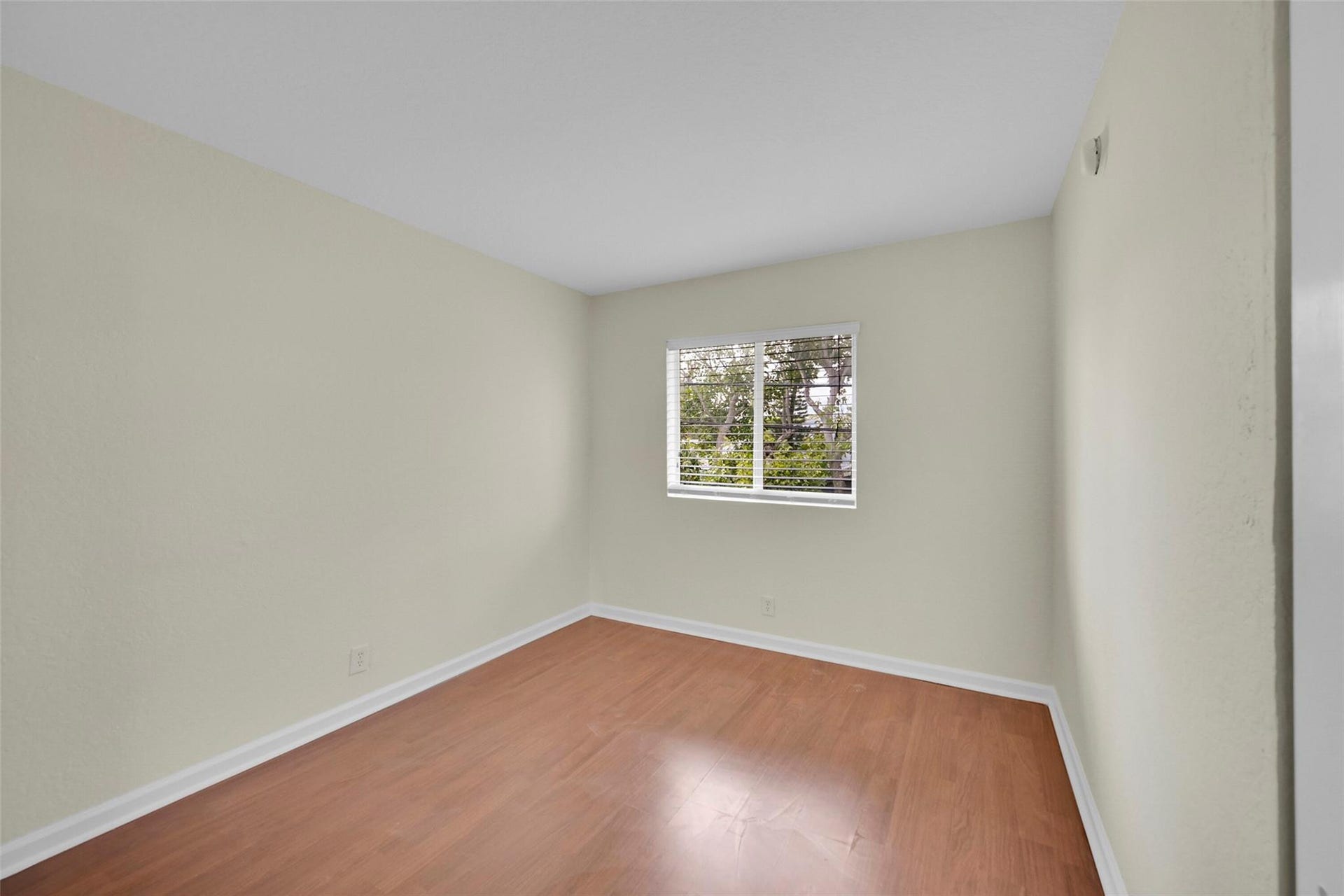 2655 NE 8th Avenue, #Apt 210, Wilton Manors, FL 33334 Wood-finish flooring with white trim, light-colored walls, and a window with horizontal blinds